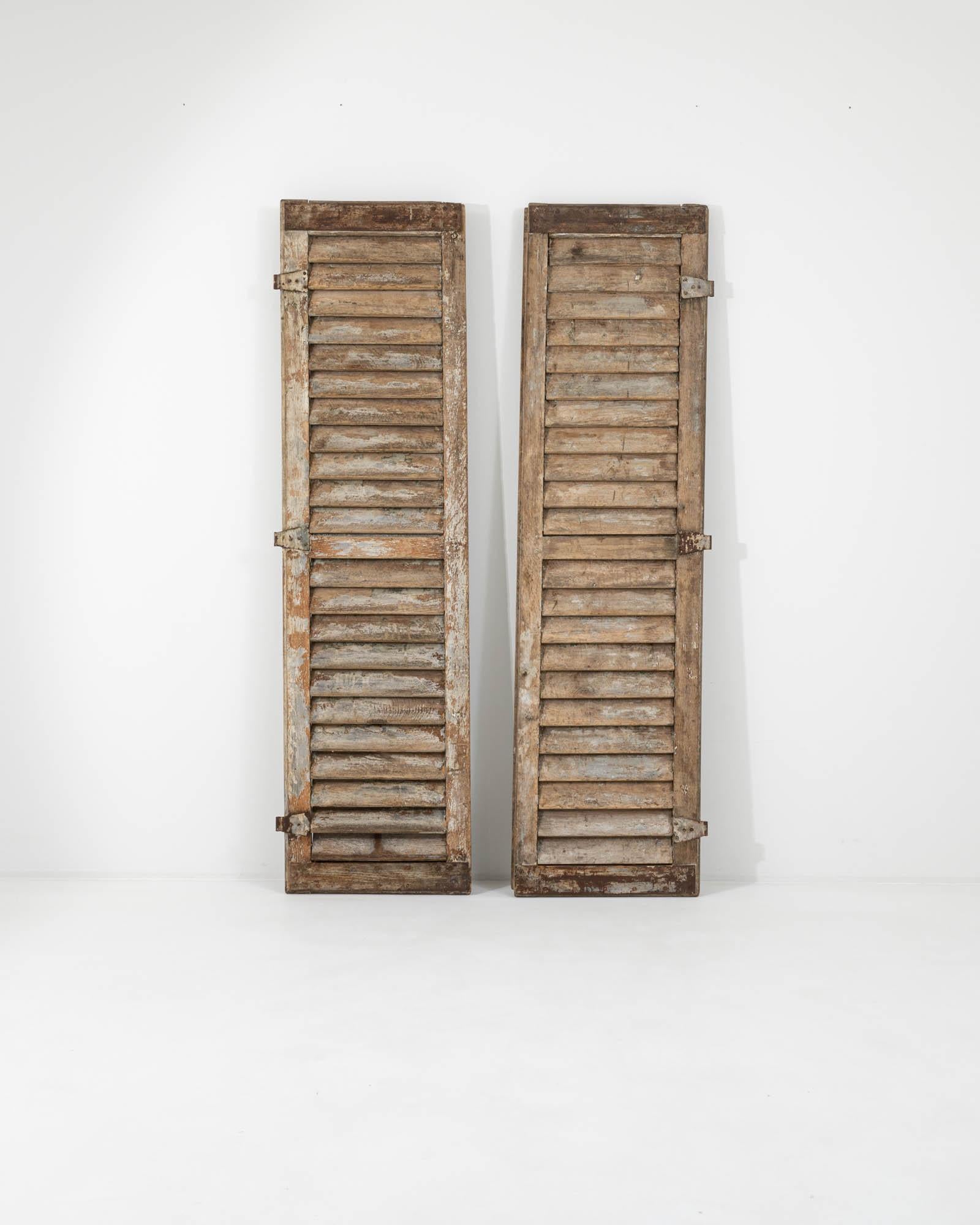 The nostalgic finish and striking height of this pair of antique wooden shutters makes them a unique accent. Built in France in the 1800s, the design is typical of high-windowed town houses and provincial chateaus. The angled slats allow air to
