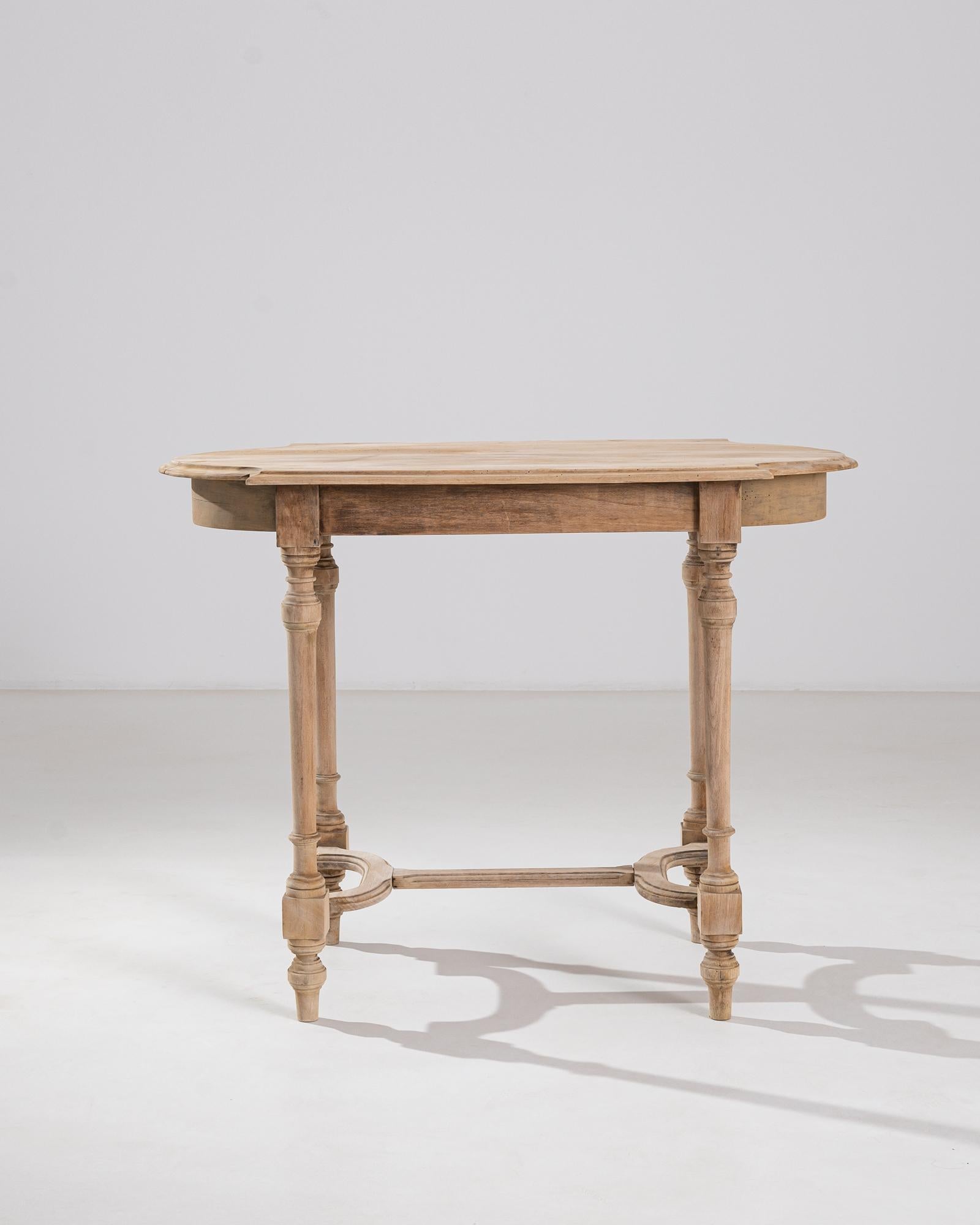 A French 19th century side table made from bleached beech wood. The table’s top is sculpted into a unique rectangle with round extensions, setting the playful and elegant tone of its silhouette. Below, criss-crossing stretchers connect via lathed