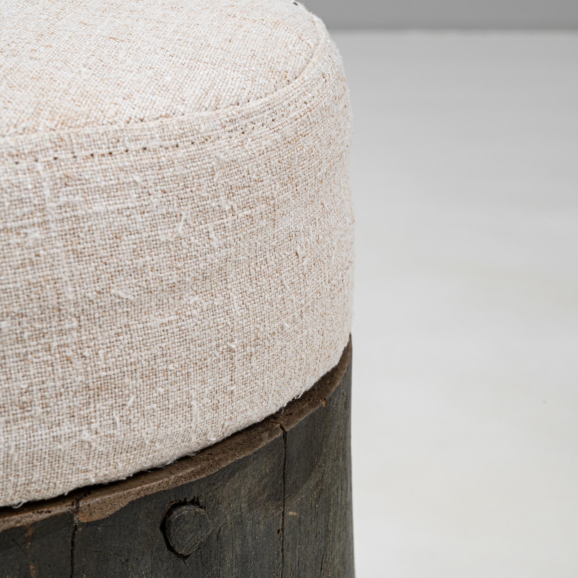 This exquisite 19th-century French wooden stool captures the essence of rustic sophistication with its robust wooden base featuring a tapered silhouette and natural dark patina. The stool is complemented by a delicately upholstered seat in a neutral
