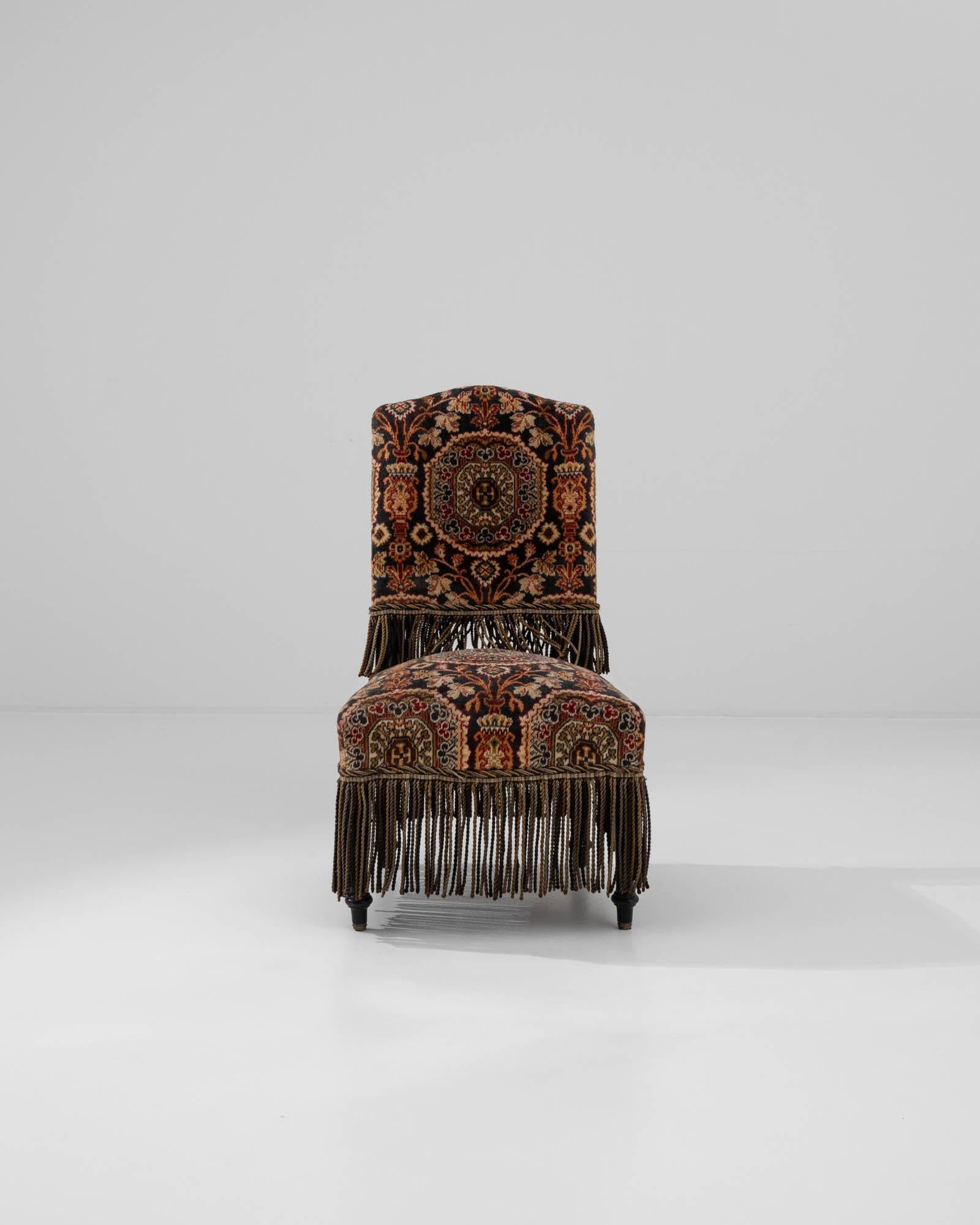 A wooden upholstered armchair created in 19th century France. Lavishly decorated and elegantly shaped, this armchair greets one with a dignified posture. A spectacular arrangement of geometric and floral motifs shine across the upholstered seat and