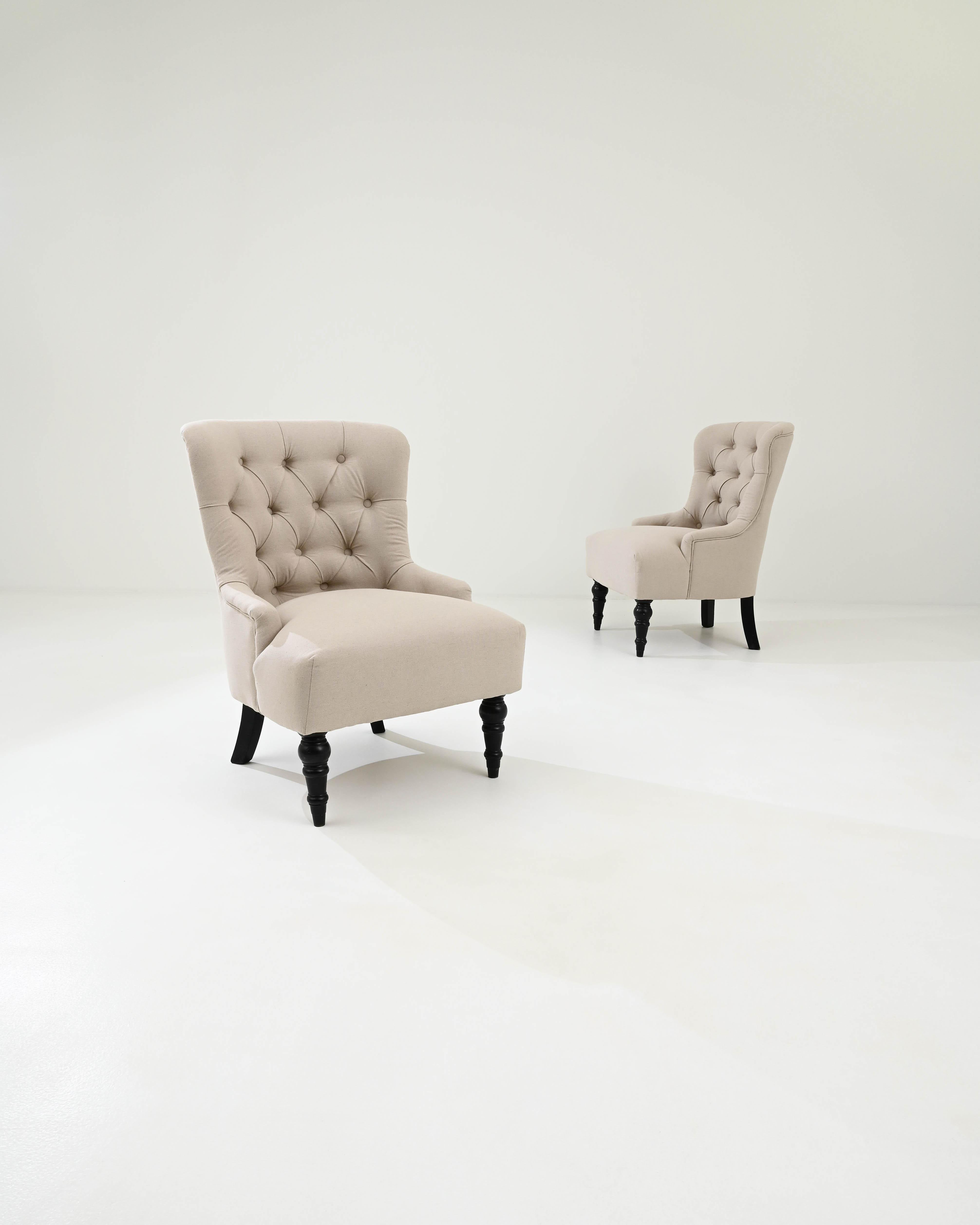 A pair of wooden upholstered armchairs created in 19th century France. Rotund and comfortable, yet also poised and dignified, this pair of chairs offers a distinguished place for a moment of rest. The freshly upholstered off-white seats and backs
