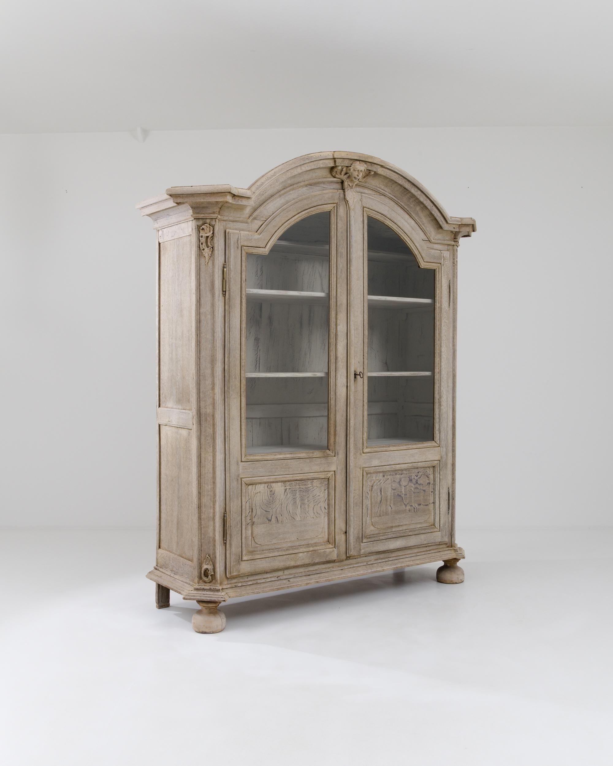A wooden vitrine made in 19th century France. Exuding a grand and inviting aura, this vitrine towers overhead, dazzling with its design and details. The surface of this vitrine’s wood has been carefully restored through a bleaching process which