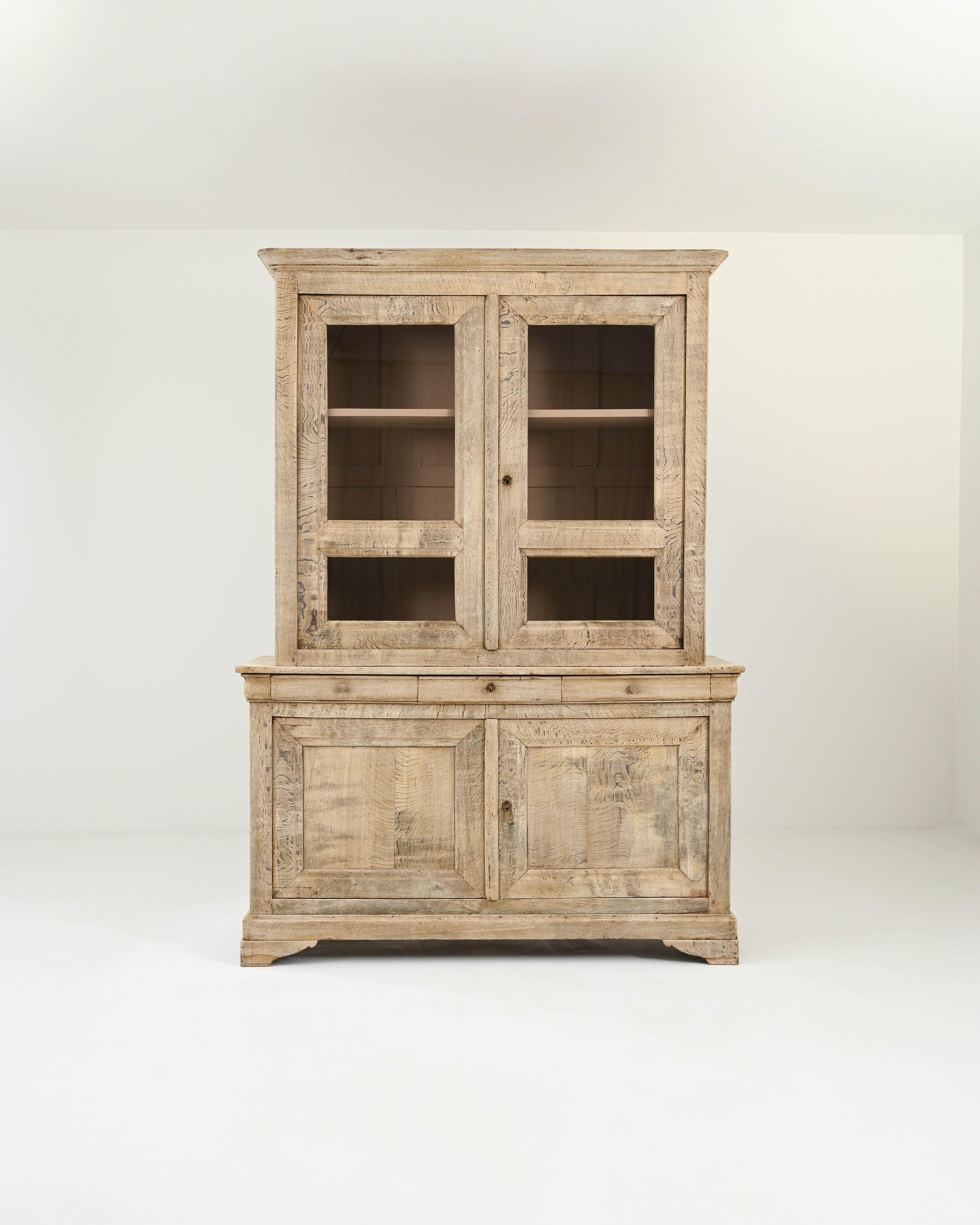 Tiger stripe-like flashes of wood grain that dart across the surface of this characteristic oak vitrine created in 19th century France. Impressive in stature, this display cabinet combines a rustic familiarity with elite craftsmanship and impeccable