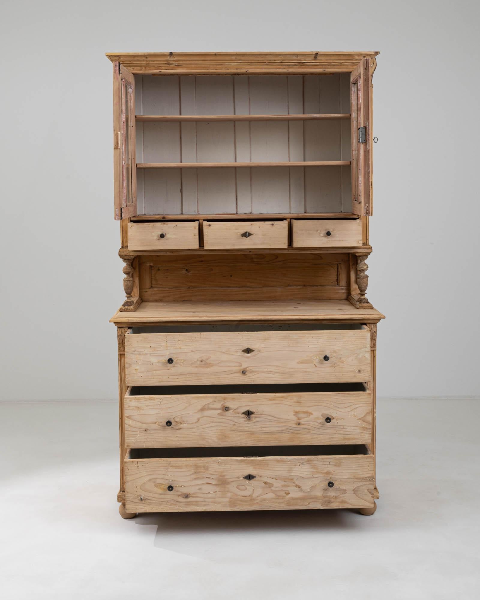 This 19th Century French Wooden Vitrine exudes the charm and elegance of a bygone era. The warm, honey-toned wood is beautifully crafted into a timeless design, featuring a spacious lower cabinet with smoothly gliding drawers, accented with