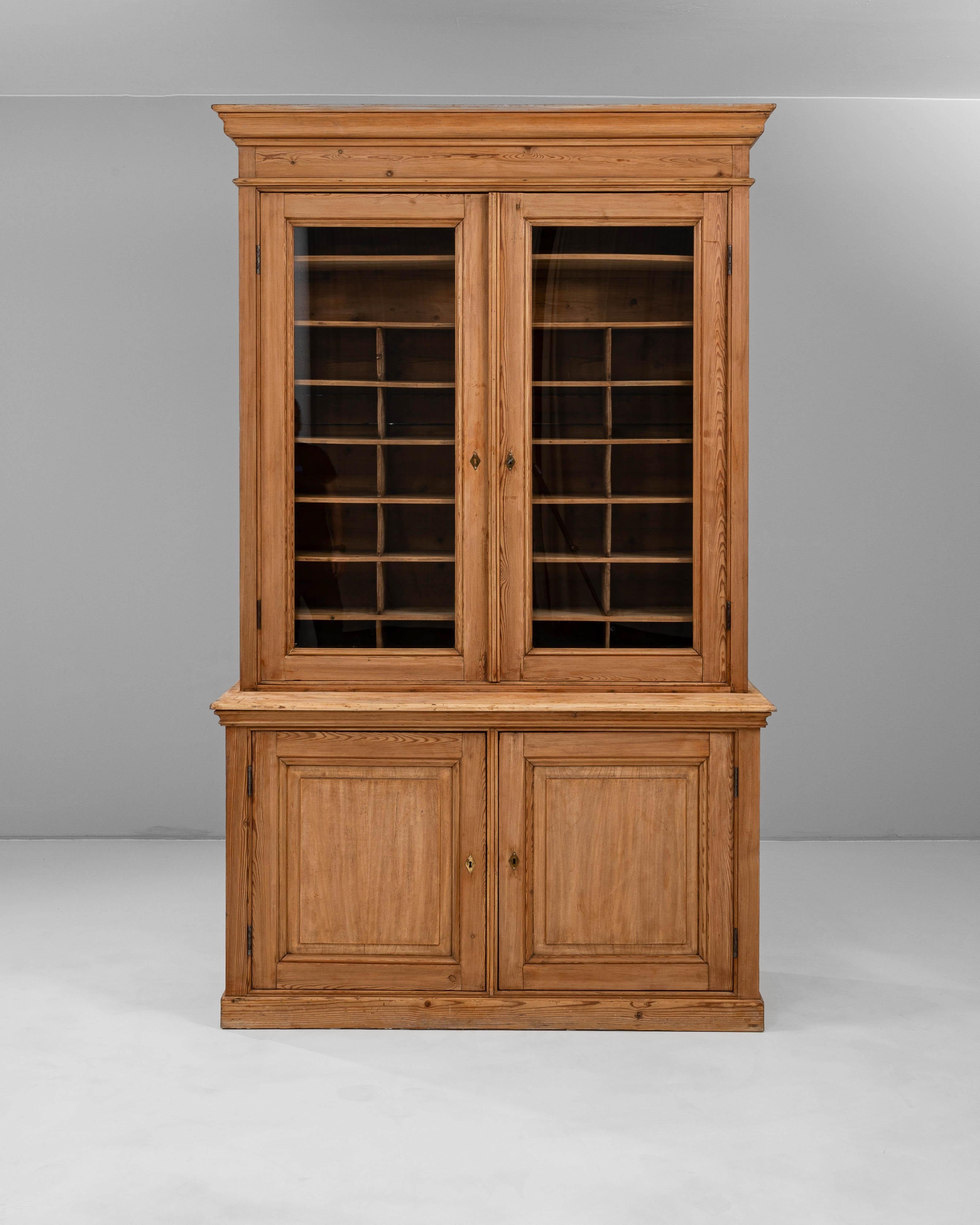 Questa vetrina in legno francese del XIX secolo incarna l'eleganza e la praticità dell'arredamento tradizionale francese. Realizzato in legno massiccio con una calda patina naturale, presenta ante superiori rivestite in vetro che si aprono per