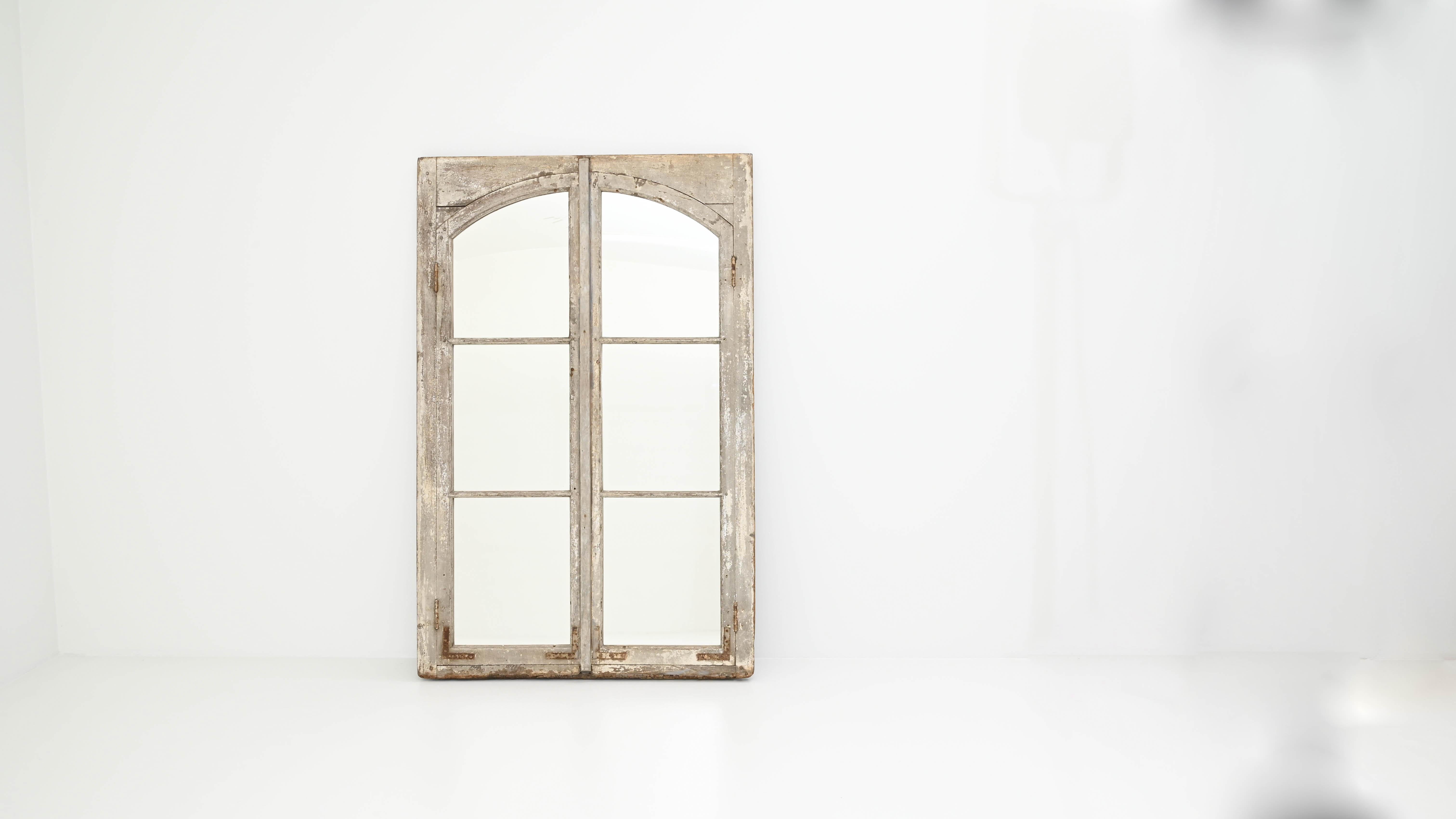 Elegant and evocative, this antique window mirror makes a unique accent for a garden or interior. Made in France in the 1800s, the mullioned wooden frame evokes the tall windows of French chateaus and country houses. The original white-painted