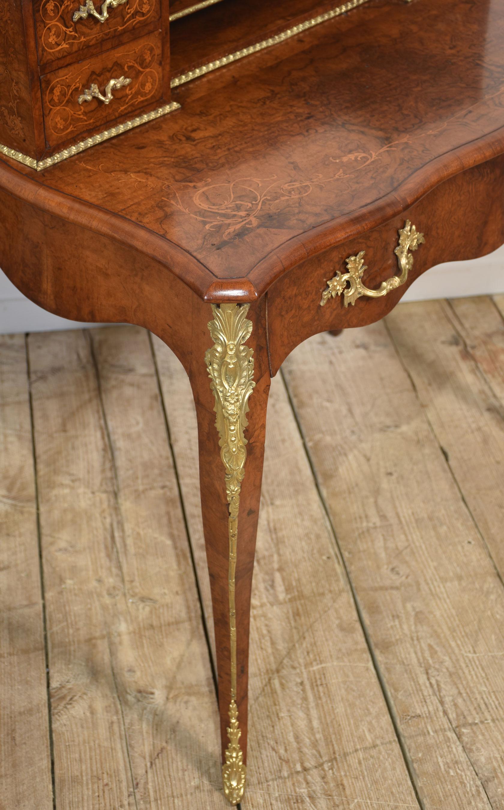 This exquisite 19th-century French writing desk, or bureau de dame, showcases the elegance and craftsmanship of the Louis XV style. The desk features a finely figured burr walnut veneer with delicate floral marquetry inlay, accentuated by ornate