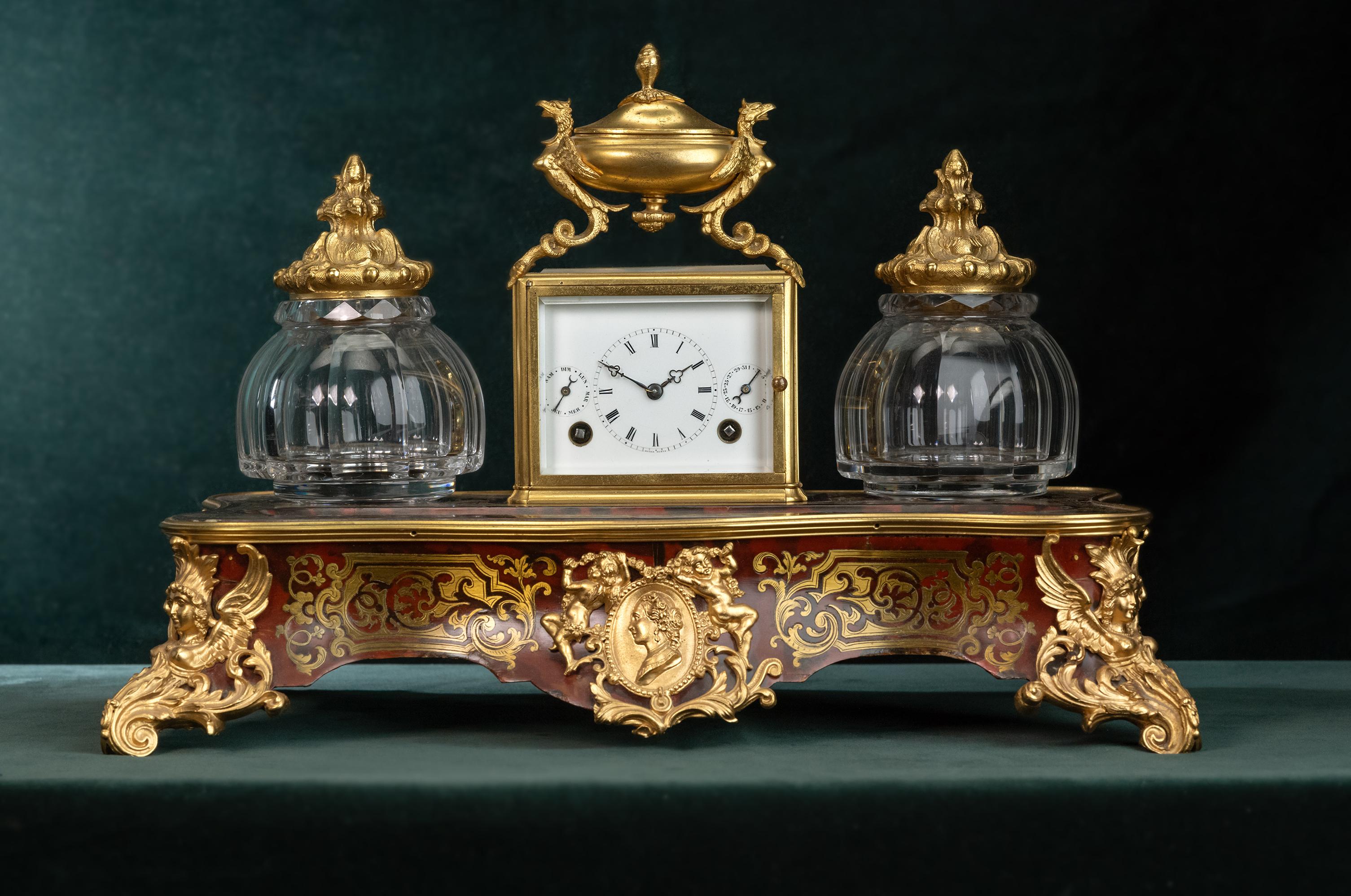 Un orologio da viaggio eccezionalmente raro integrato in un set da scrittura, composto da un calamaio e da una sabbiera. Il set è montato su una base di legno ornata con tartaruga, ottone intarsiato e ornamenti dorati. L'orologio da viaggio presenta