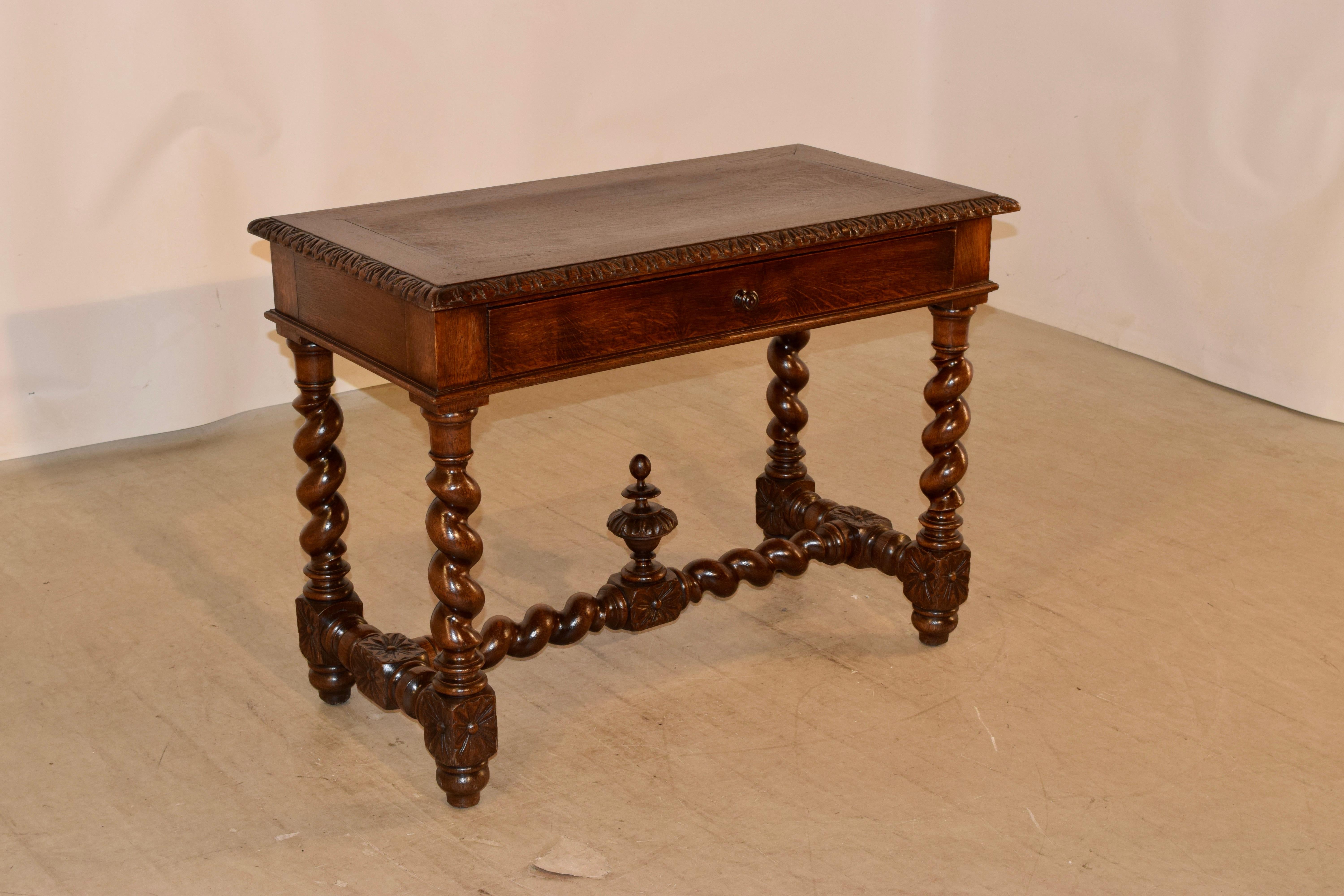 19th century French oak writing table with a banded edge around the top, surrounded by a hand carved decorated beveled edge. This follows down to a simple apron, containing a single drawer in the front, over hand turned barley twist legs, joined by
