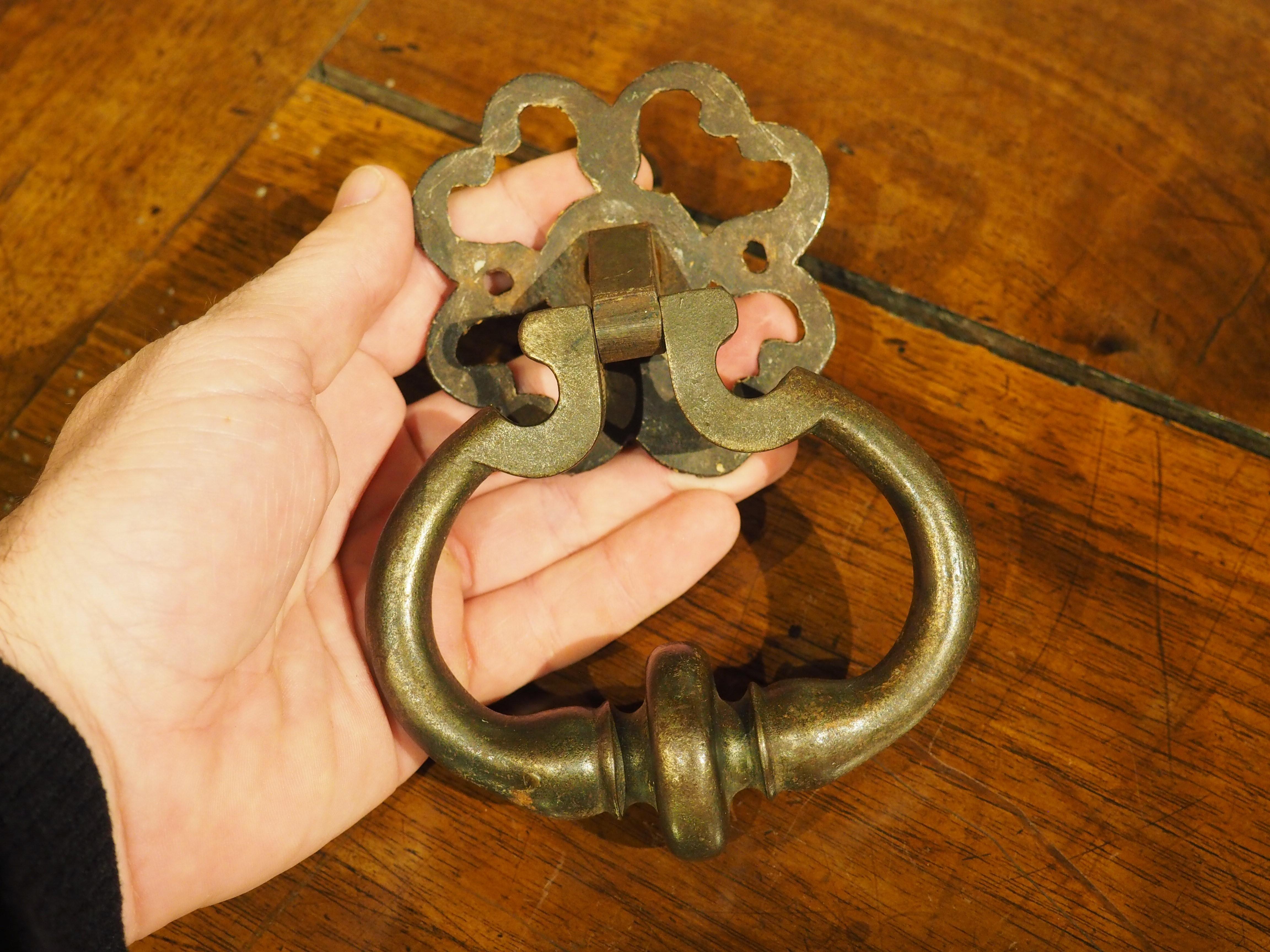 Hand-crafted in France in the 1800’s, this wrought iron door knocker features a pierced quatrefoil backplate. There are two small holes on the sides, where nails would help support the weight of the iron. There is also a larger central hole, which