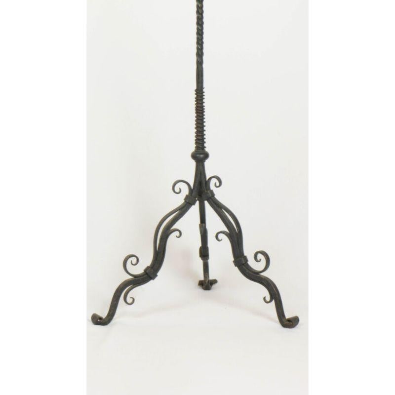 Wrought iron floor candelabra with a twisted square center stem and twirled vine decoration with flowers. It has three arms, the center one has a large candlecup, and the arms on each side have flower shaped bobeches and candlespikes. The center