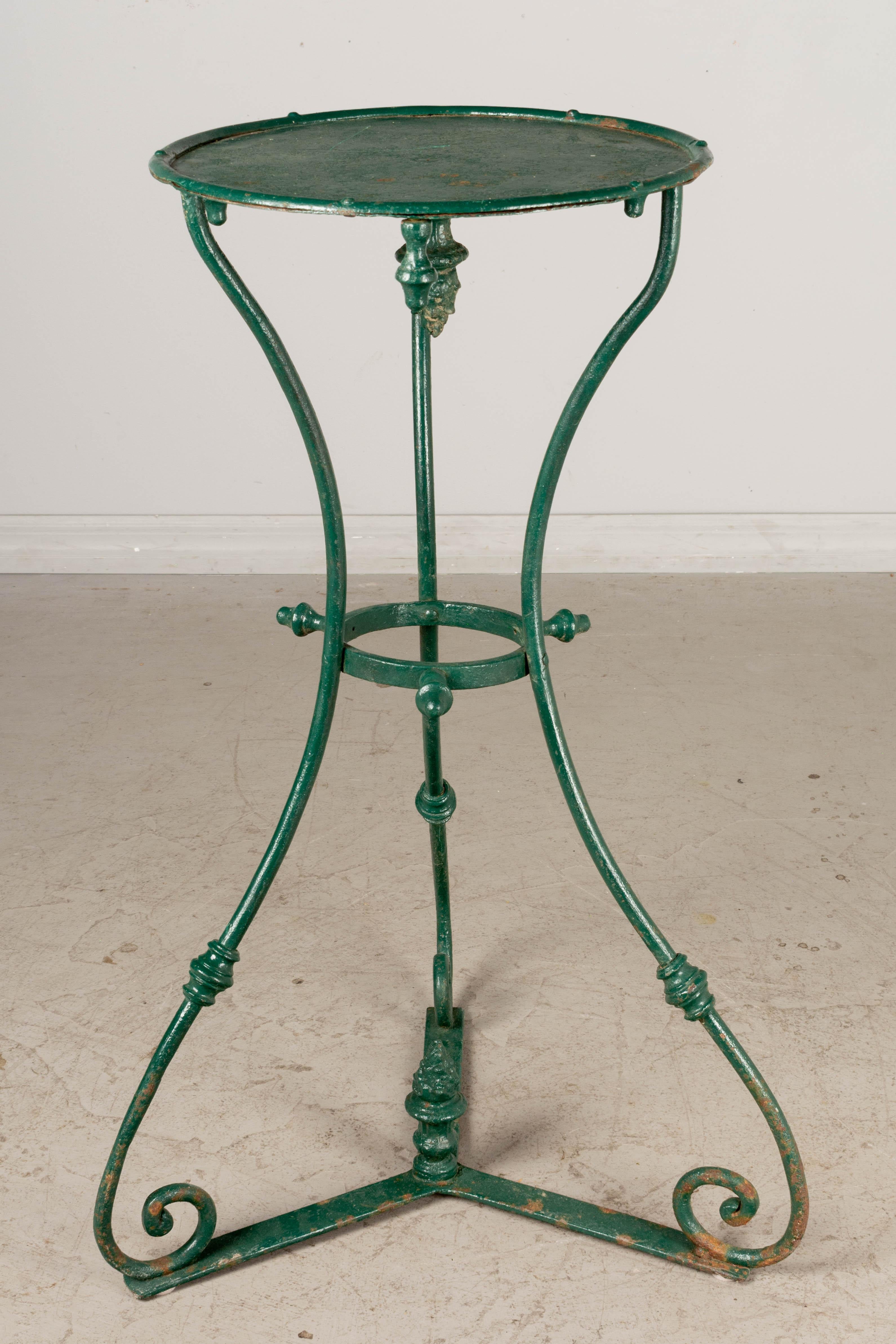 A 19th century French green painted wrought iron gueridon garden pedestal or plant stand. Tripod base with tôle top and decorative cast iron finials. 
35