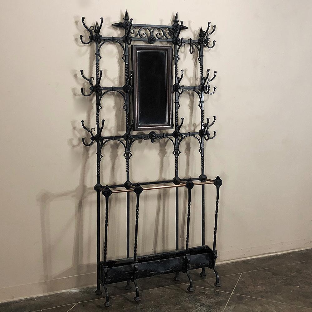 19th century French wrought iron hall tree is a marvel of the metalsmith's art! Intricate scrollwork, twisted rod, and spiral finials abound, with a wood framed mirror on gimbals and an umbrella stand below to keep the wetness under control. An