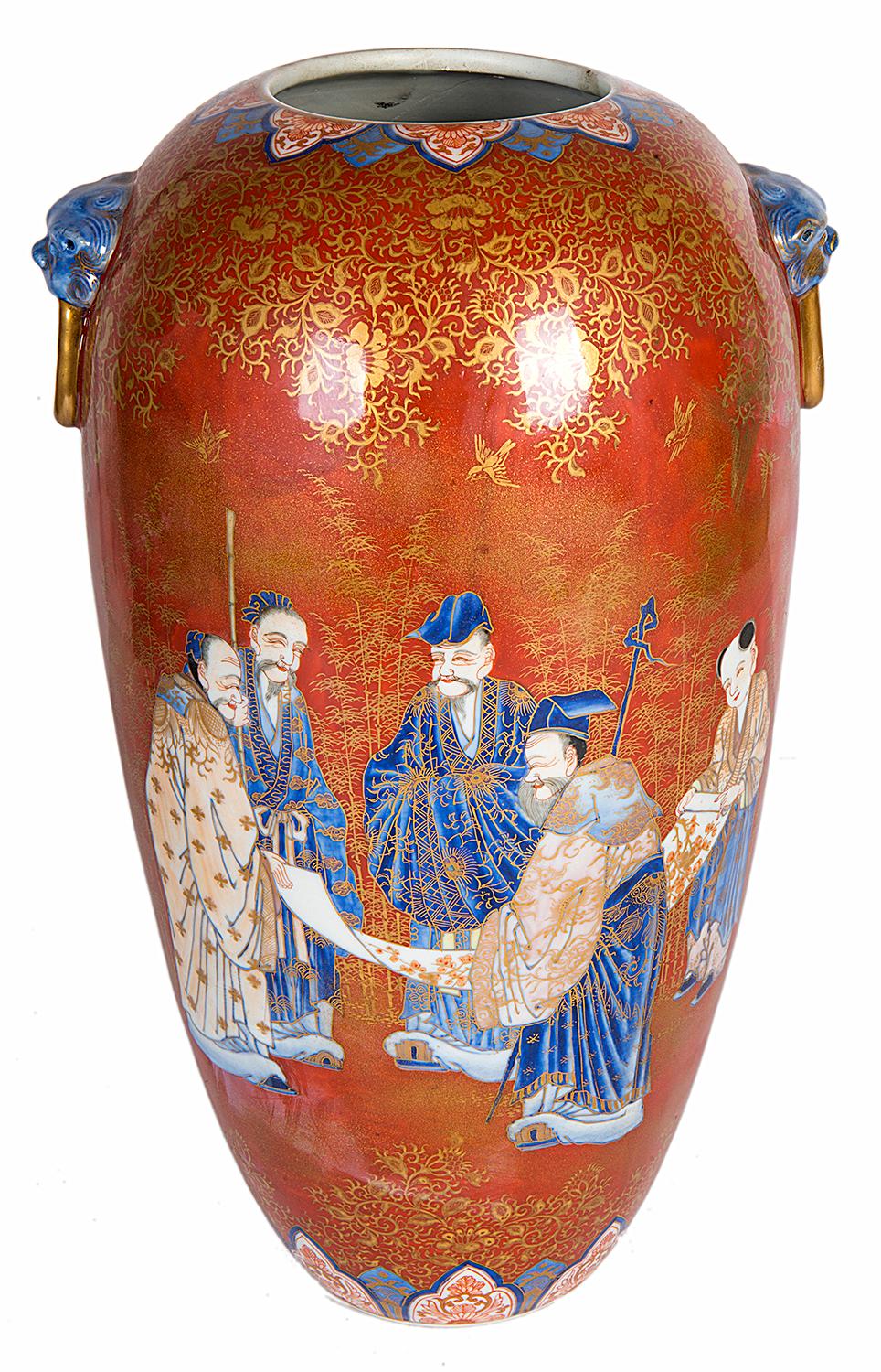 Jarrón de porcelana japonesa Fukagawa del siglo XIX, de muy buena calidad. Con fondo anaranjado con decoración foliada dorada, asas en forma de anillo con máscara de león y varios eruditos sosteniendo un pergamino.