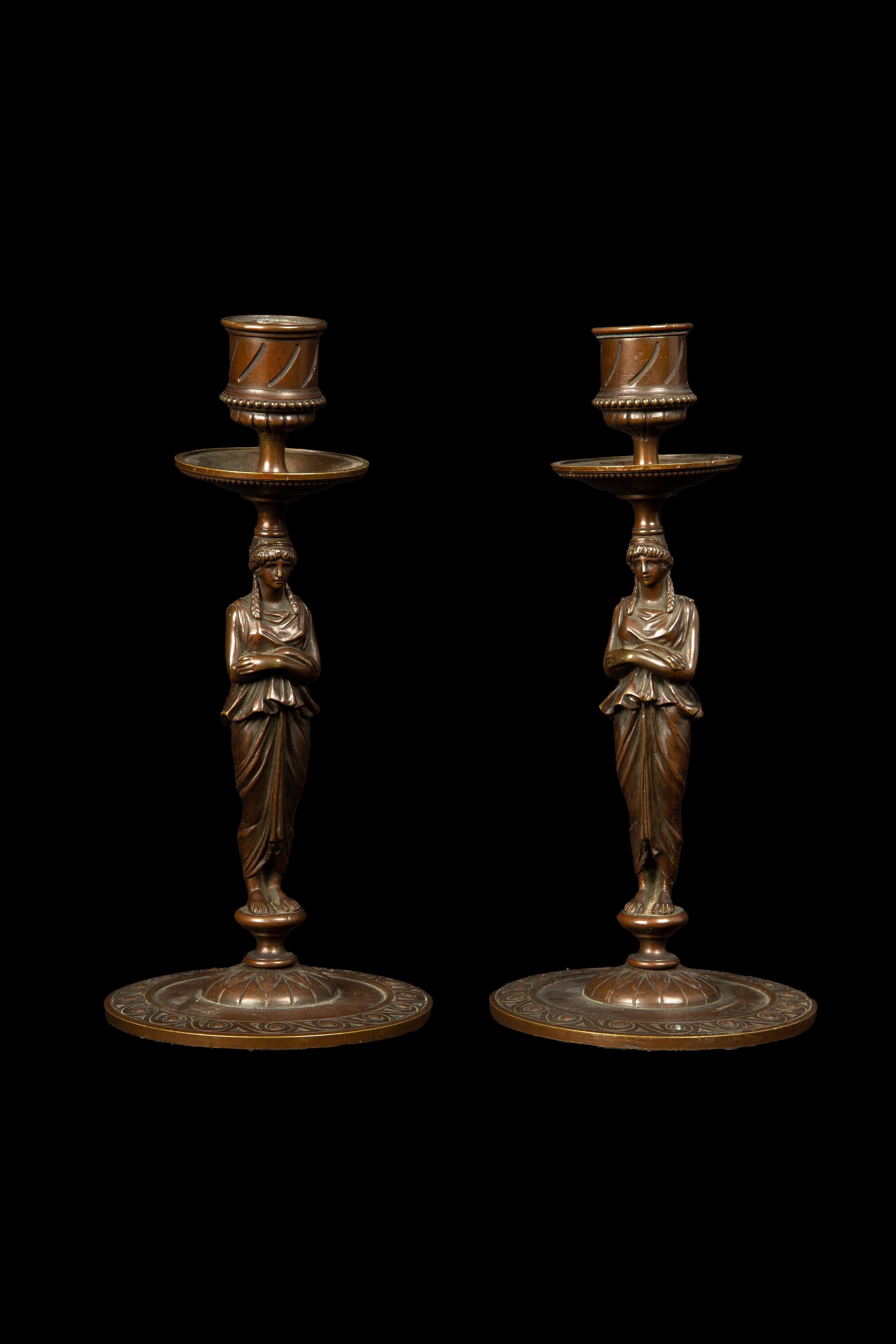 19th Century Bronze Full Body Greek Revival Caryatid Candlestick pair. These candlesticks exude timeless elegance, inspired by the Greek Revival period. Meticulously crafted from high-quality bronze, they showcase intricate caryatid figures holding