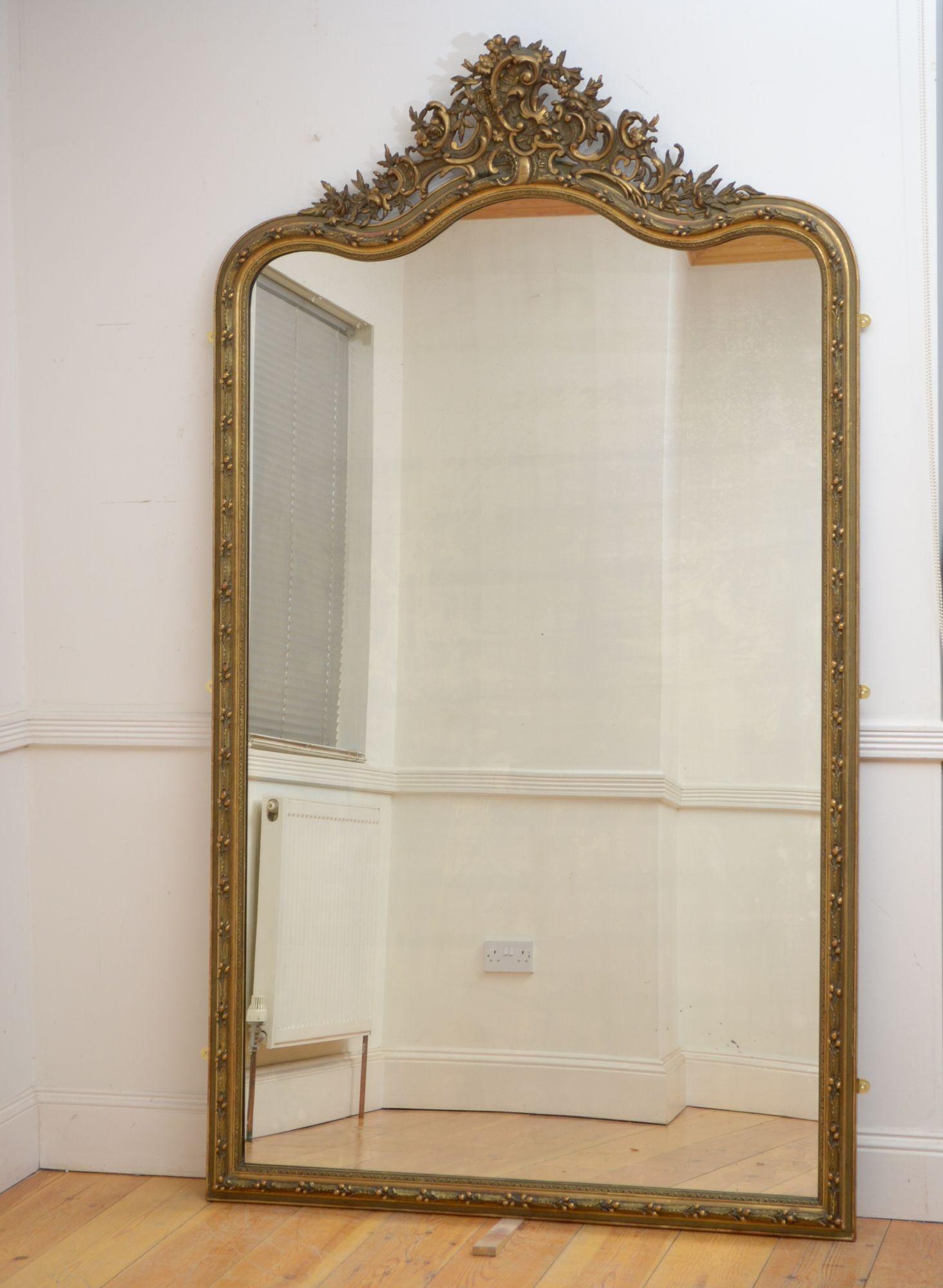 Sn5397 Superb XIXth century French gilded leaner or wall mirror, having original glass with minor imperfections, in moulded and gilded frame decorated with holly leaf and berries throughout and extensive crest with flowers, leaves and scrolls. This