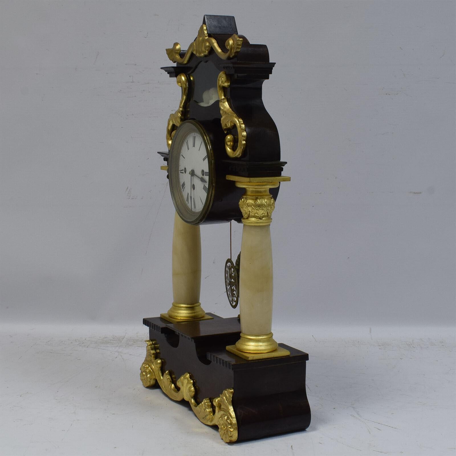 Voici cette exquise horloge à colonne fonctionnelle du XIXe siècle, véritable témoignage de l'élégance de l'époque. D'une hauteur de 61 cm, cette horloge de cheminée ancienne présente un portique soutenu par deux colonnes d'albâtre blanc, créant