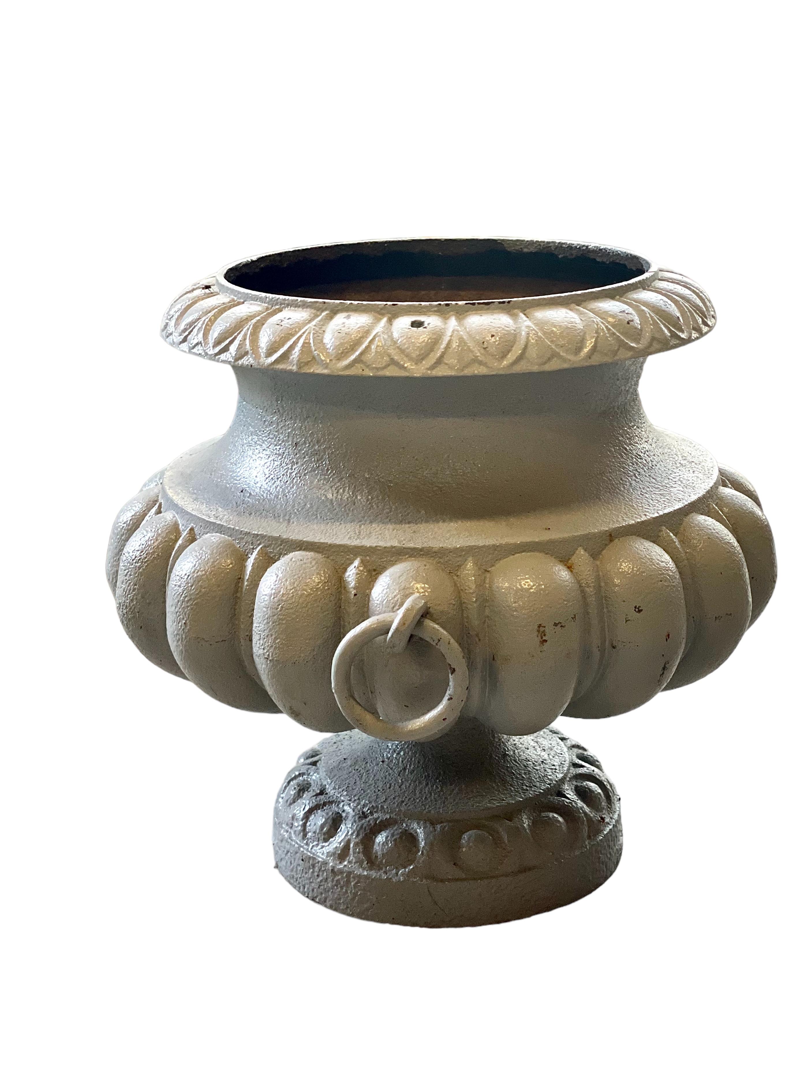 A superb example of a late 19th century garden urn, in the classical French style. This elegant planter features a heavy, cast-iron construction, drop ring handles, a raised pedestal base and an attractive, grey-laquered finish. ‘Feuilles d’eau’