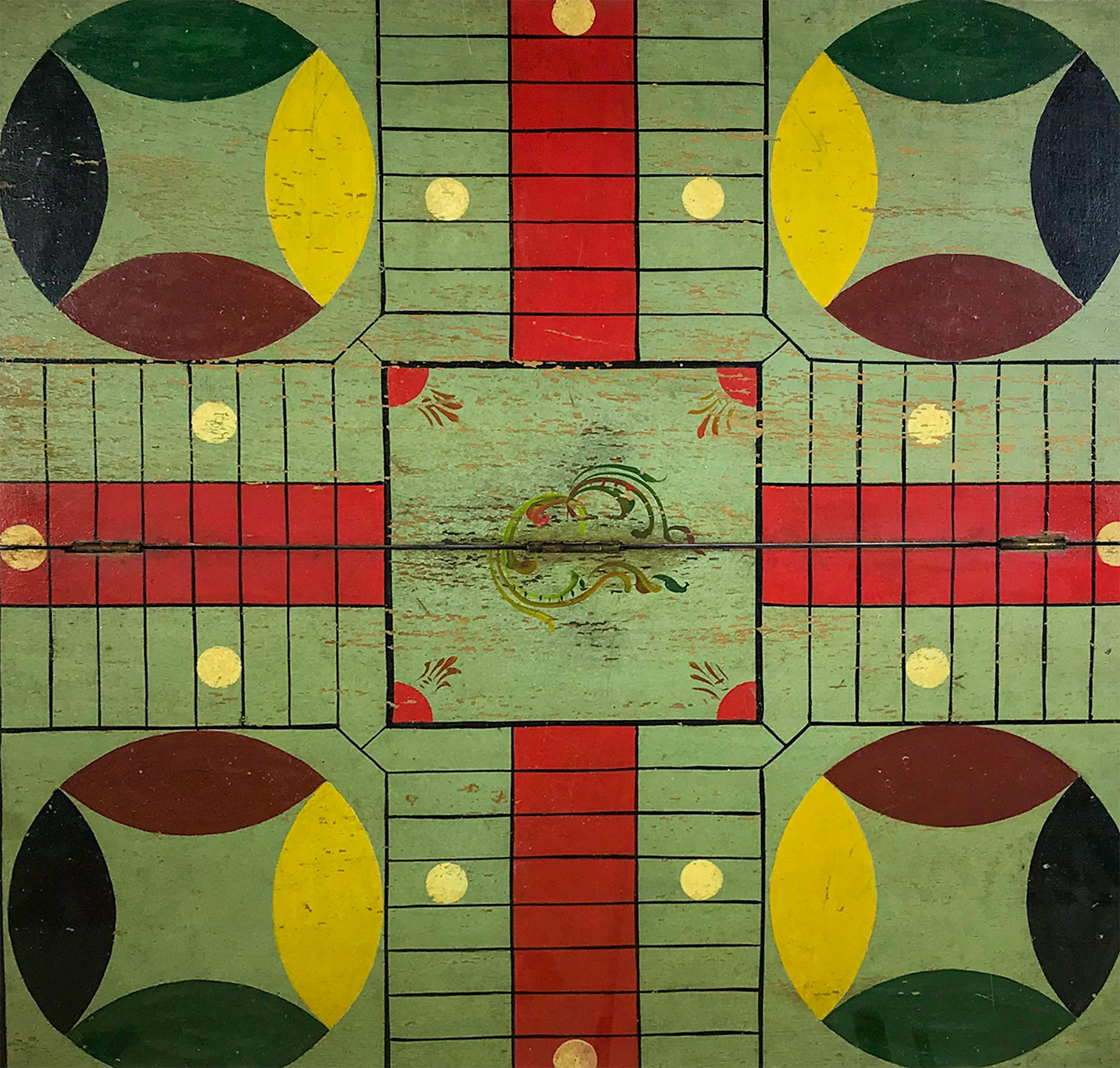 A fold out Parcheesi board that is mounted against linen and boxed in Lucite. The board is painted with eight different colors with multi-colored corner circles, a scrolled home and red playing field and a green ground with black bordering. Made of