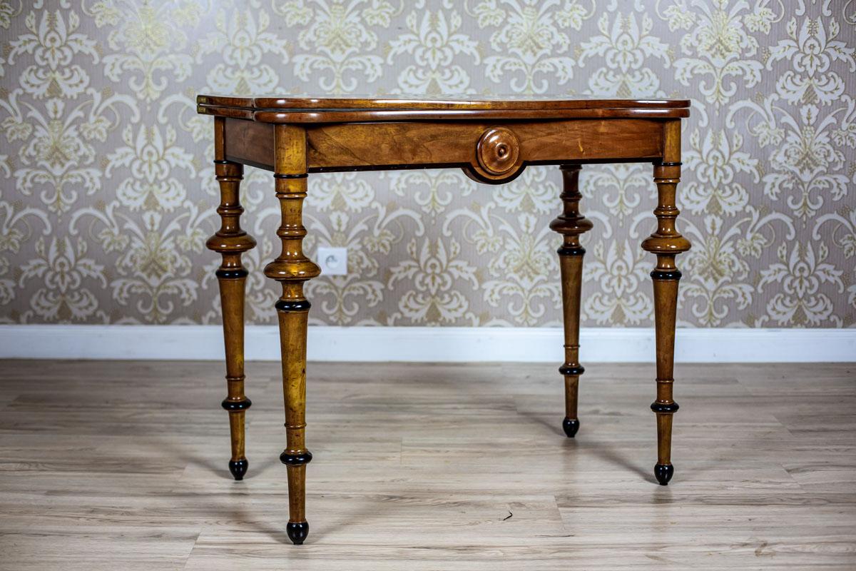 We present you a game table which can also be used as a wall table.
It is from fourth quarter of the 19th century.
This piece of furniture is made of two segments.
The table top, connected with hinges, rotates around an unsymmetrically placed