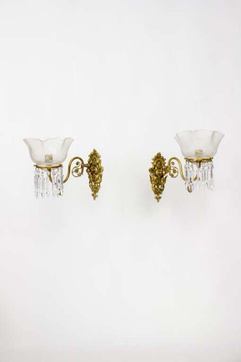 A pair of mid-19th century Victorian sconces with brass scroll arms, crytals and original glass. Attributed to Cornelius & Co due to the characteristic castings on the gas fittings. Made in the US. Arms are a smooth brass with cast morning glories