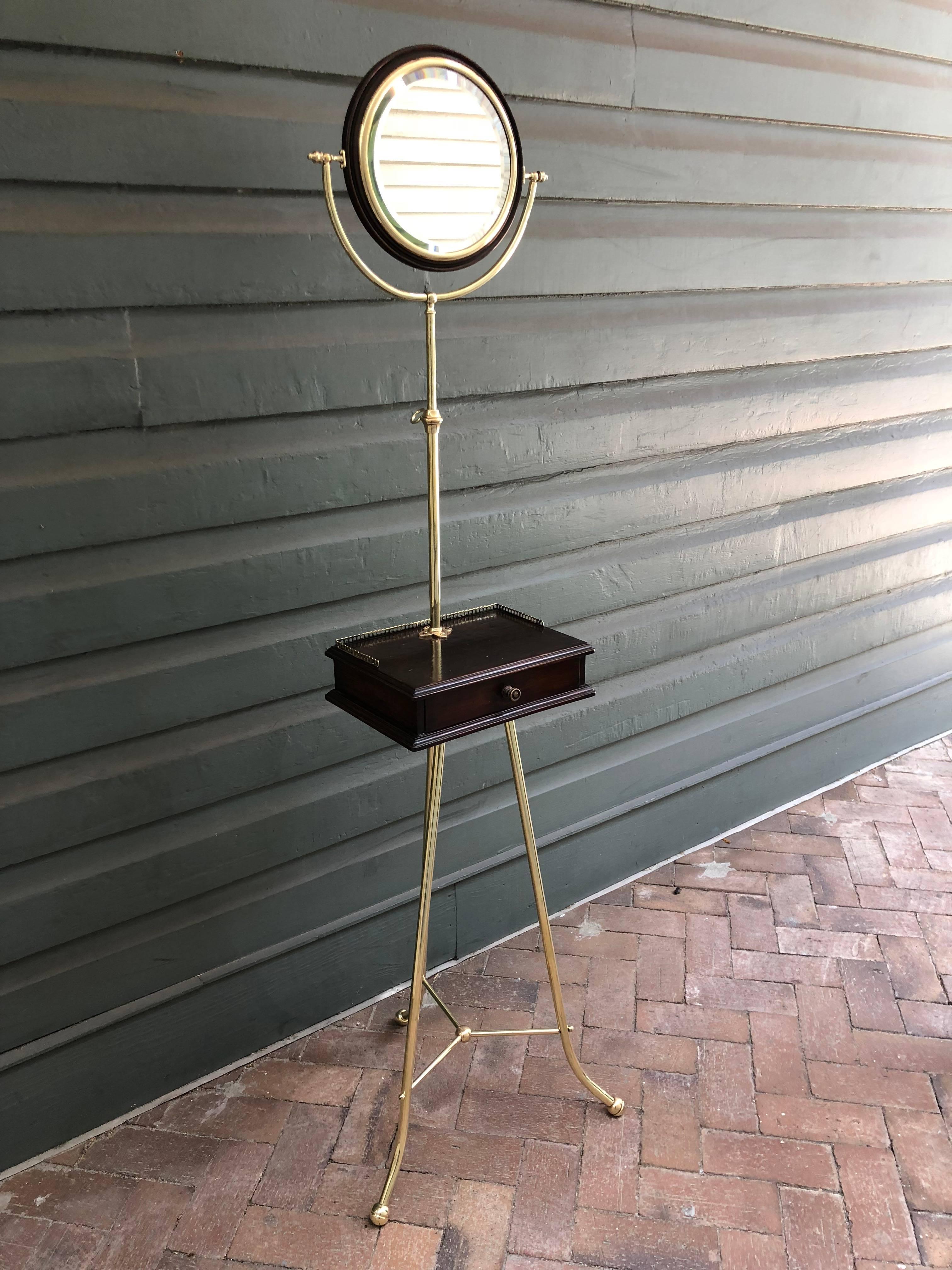 This 19th century British Colonial gentleman's campaign shaving stand is made with mahogany and brass. The looking glass is double sided with one side magnifying and one true. The mirror is mounted on a telescopic pole ending on a mahogany one