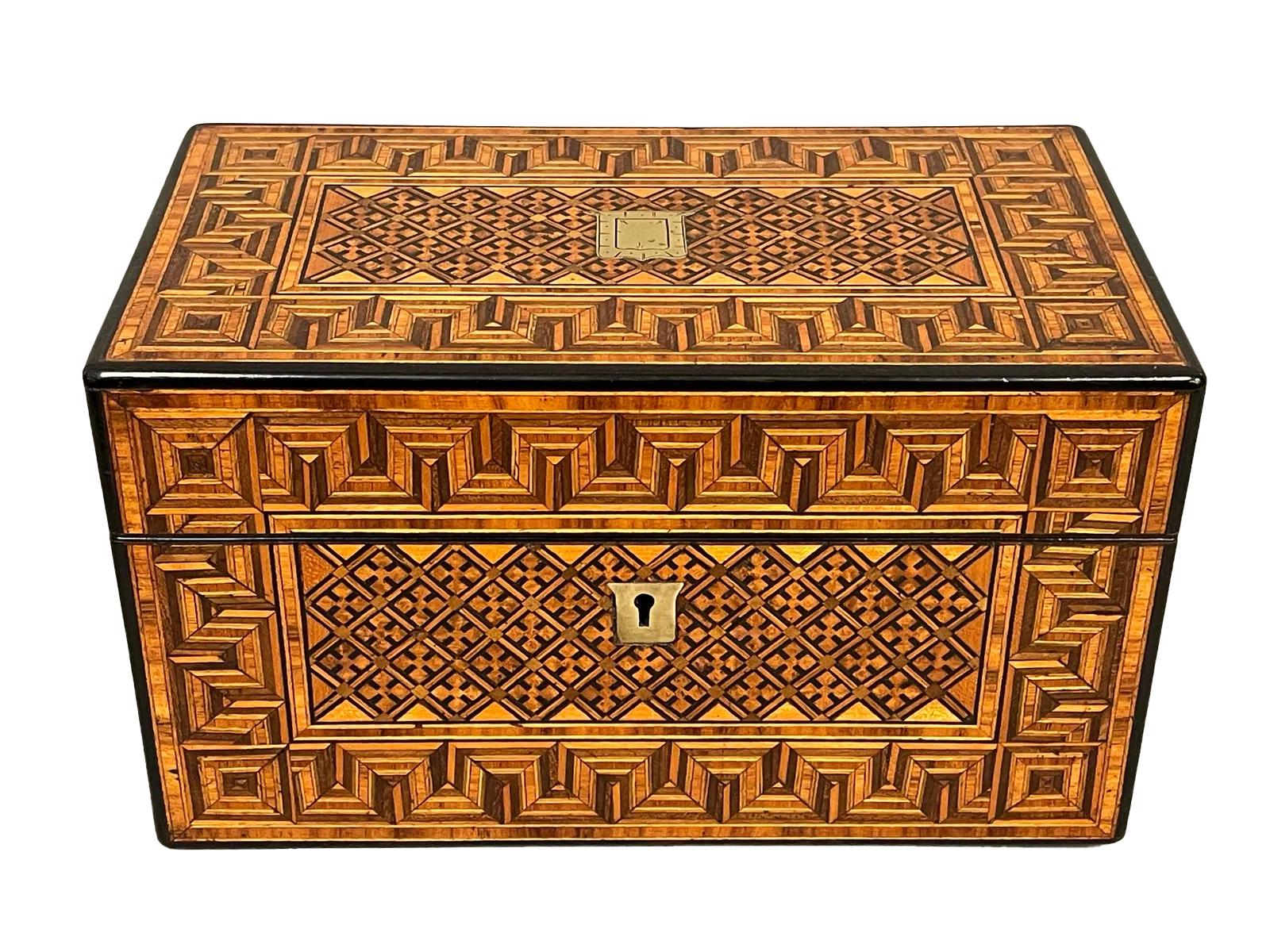 Caja de té de doble cámara con laterales y fondo de nogal con incrustaciones geométricas en la parte superior y frontal. La parte superior con bisagras se abre a un interior dividido con dos tapas de madera clara con pomos ebonizados y bordes