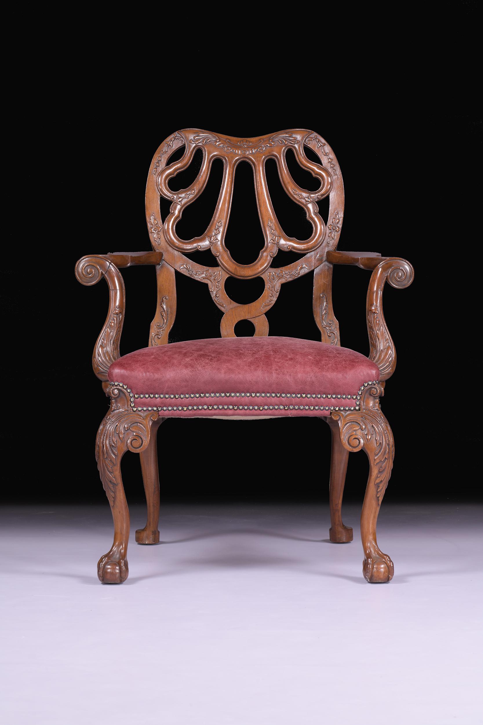 Superbe fauteuil anglais ancien du XIXe siècle de la manière de Giles. Le dossier est constitué d'une coquille stylisée ajourée et d'accoudoirs à volutes avec un décor sculpté en bas-relief, l'assise est rembourrée et repose sur des pieds cabriole à