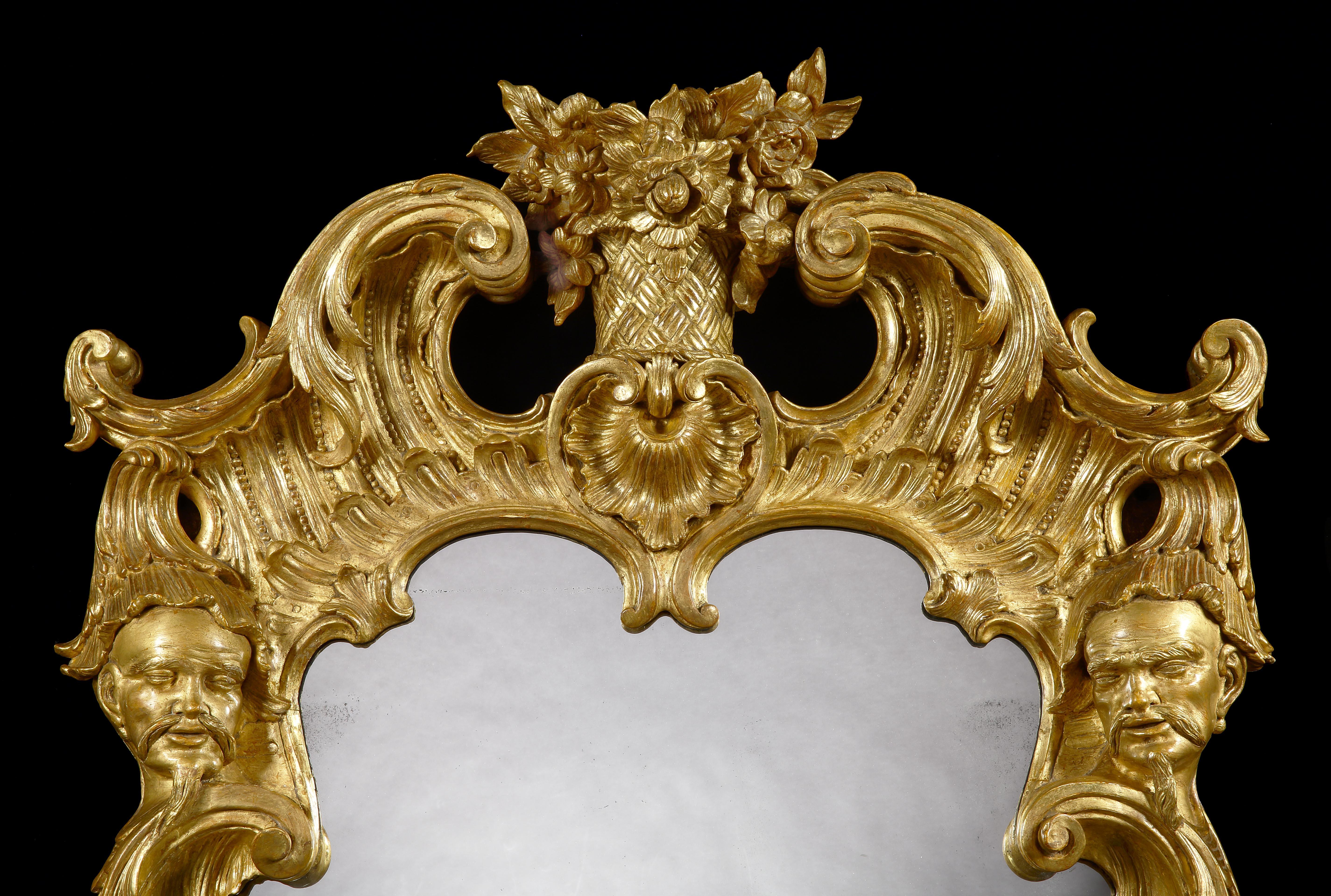 A George II Style Pier Glass in the manner of Matthias Lock

Of rectangular form, constructed in giltwood and gesso, elaborately carved incorporating filigree inner-moulding and floriate branches to the sides; above, a flower basket at the apex is