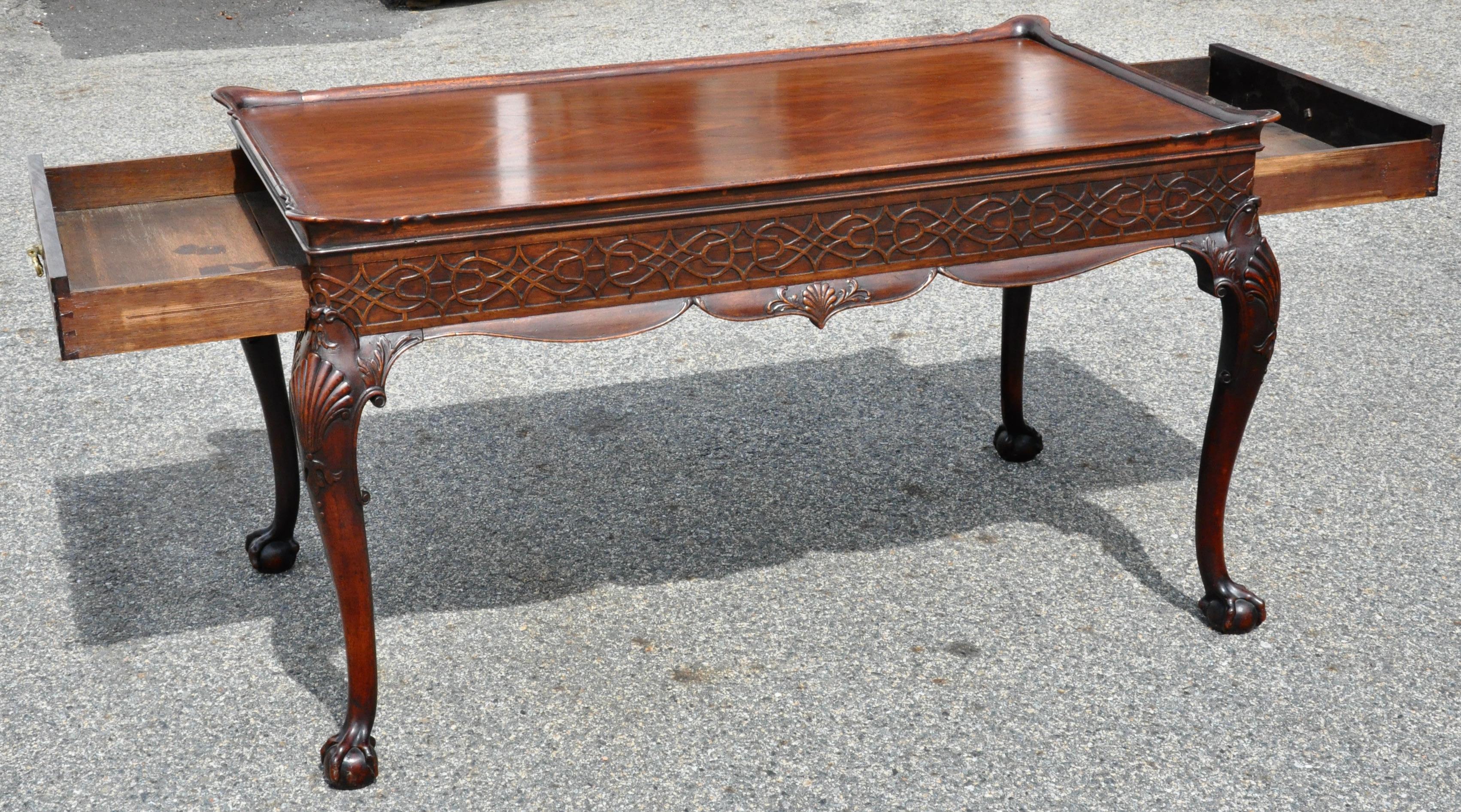 Masterfully worked solid mahogany Chippendale style serving table. Raised edge top with old growth Cuban mahogany boards. Drawers on opposing narrower ends. Carved chinoiserie fretwork in frieze all around. Finished and carved on all four sides.