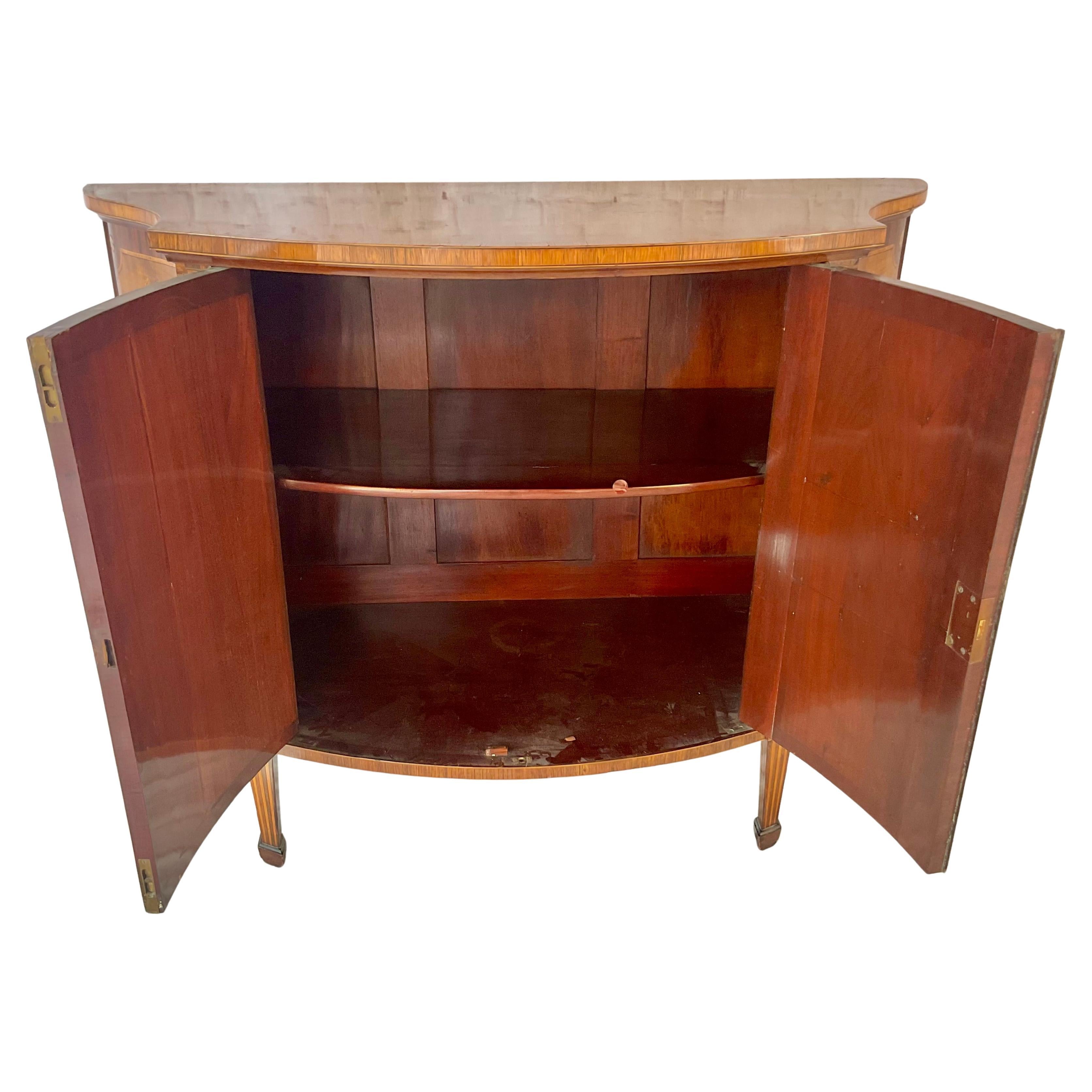 Très belle commode de style George III en bois de lièvre et marqueterie du 19ème siècle par W. Williamson and Sons, Guildford (1790-1889). La commode à façade serpentine présente des bandes transversales en bois satiné et des panneaux de marqueterie