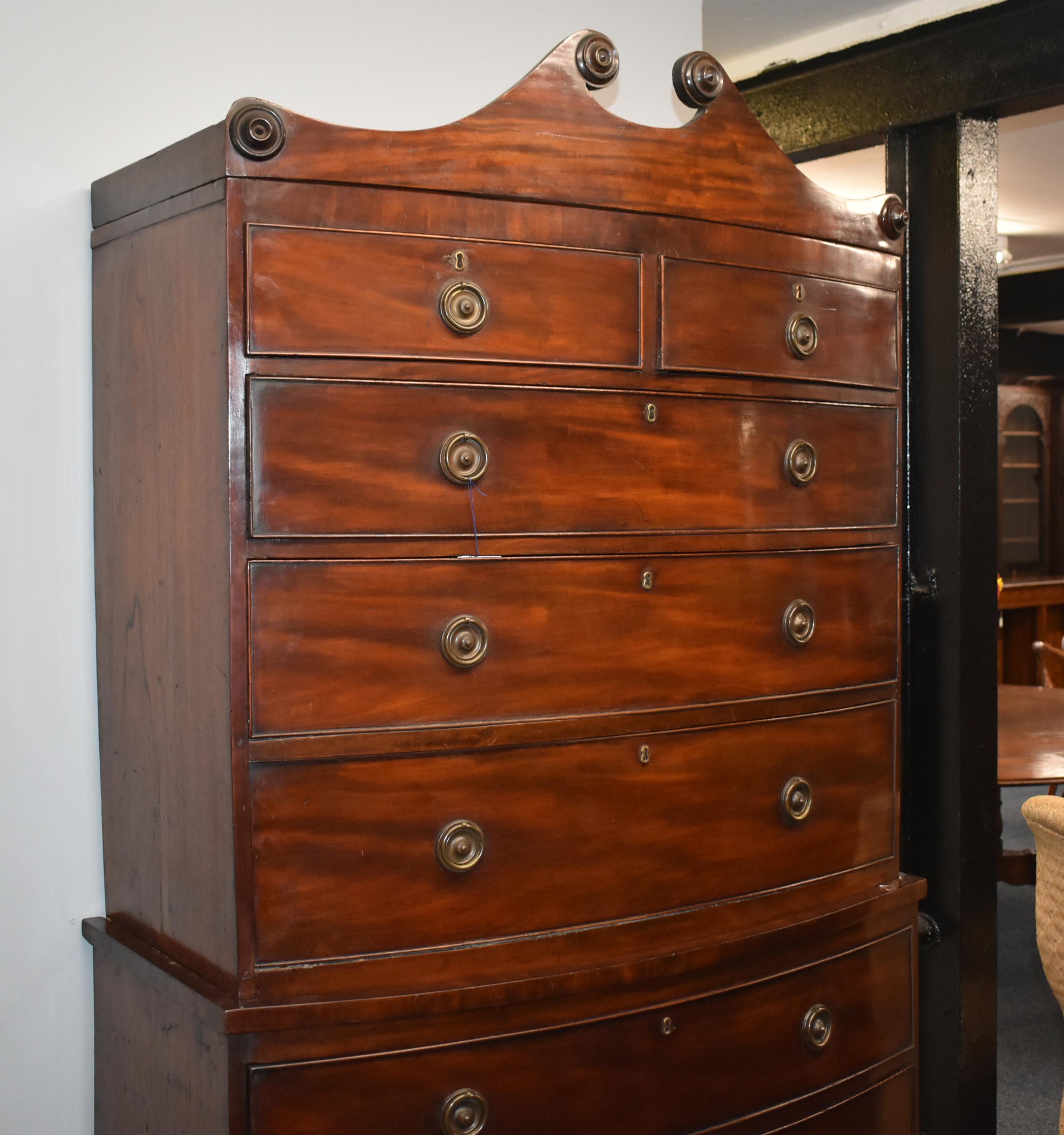 A good quality 19th century George III mahogany bow front chest on chest. The top of the chest has a small arched pediment above an arrangement of five drawers, each with brass escutcheons and brass handles. This fits onto the base chest, which has