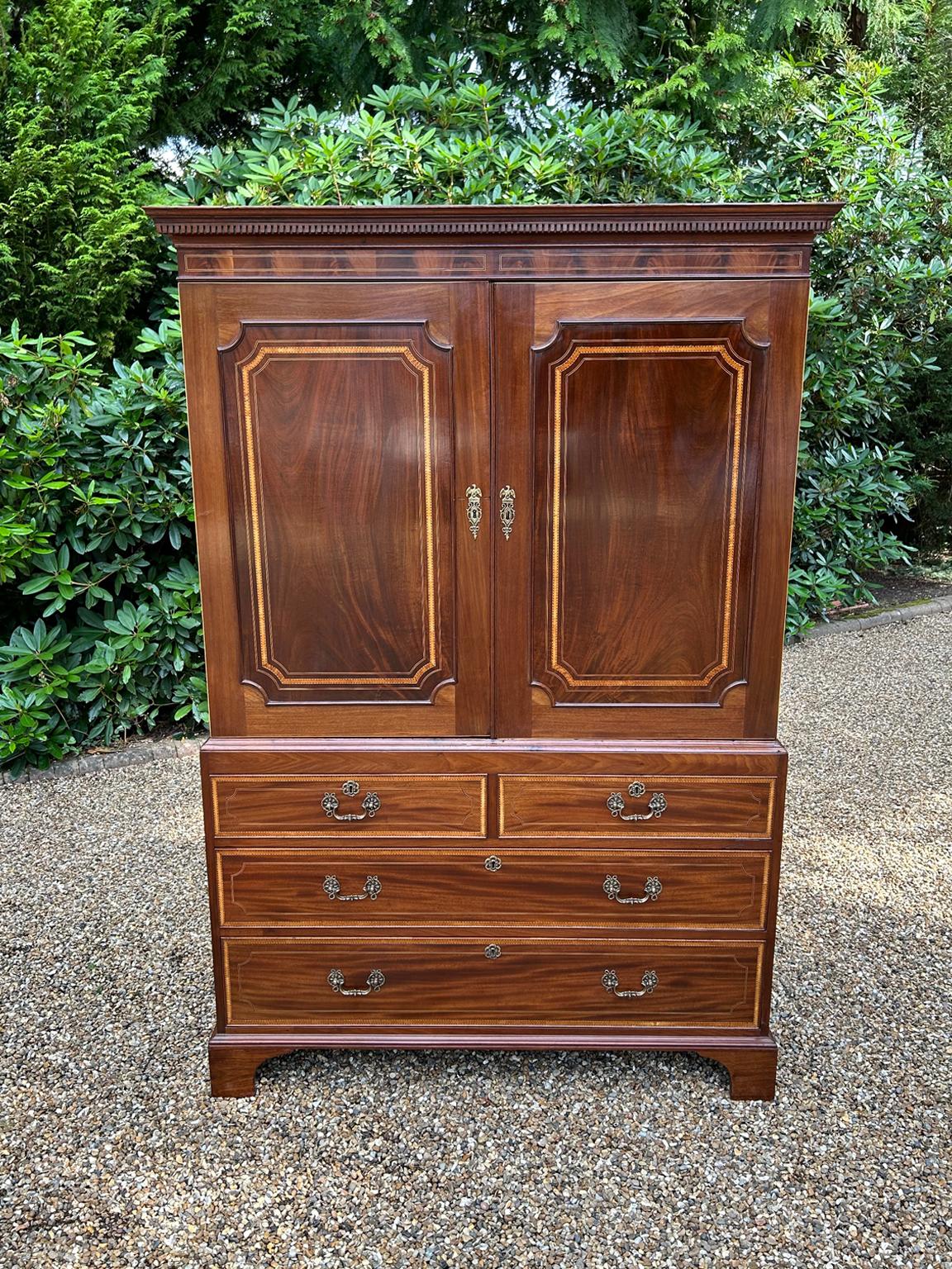 19th Century George III Mahogany Linen Press with inlaid with satinwood crossbanding throighout,  two panelled doors with five original interior sliding trays. Two short and two long drawers with original brass swan neck handles on bracket feet