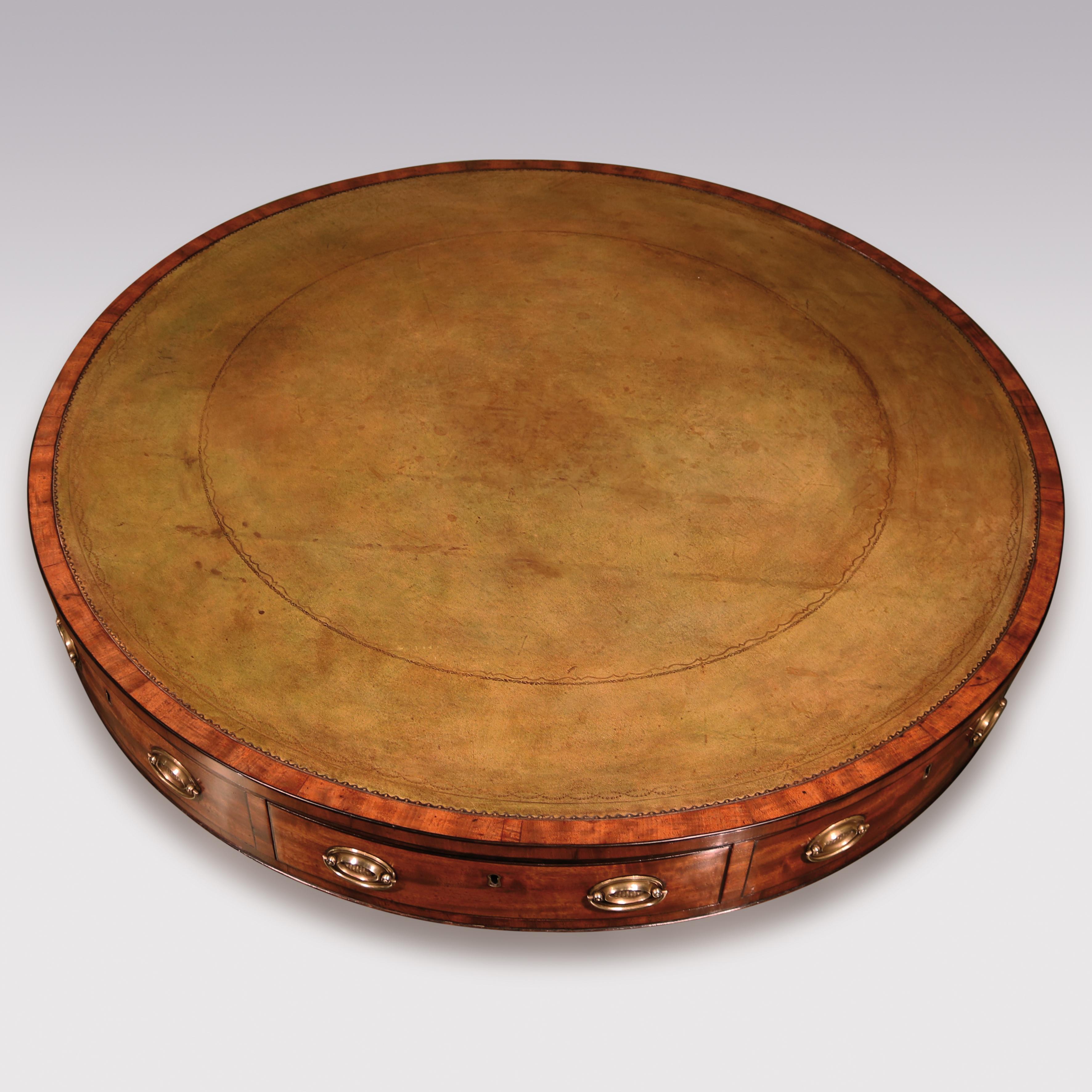 A George III period well-figured mahogany revolving drum table, ebony strung throughout, having green tooled leather circular top above frieze drawers supported on turned stem with reeded 4-splay legs ending on original brass castors.