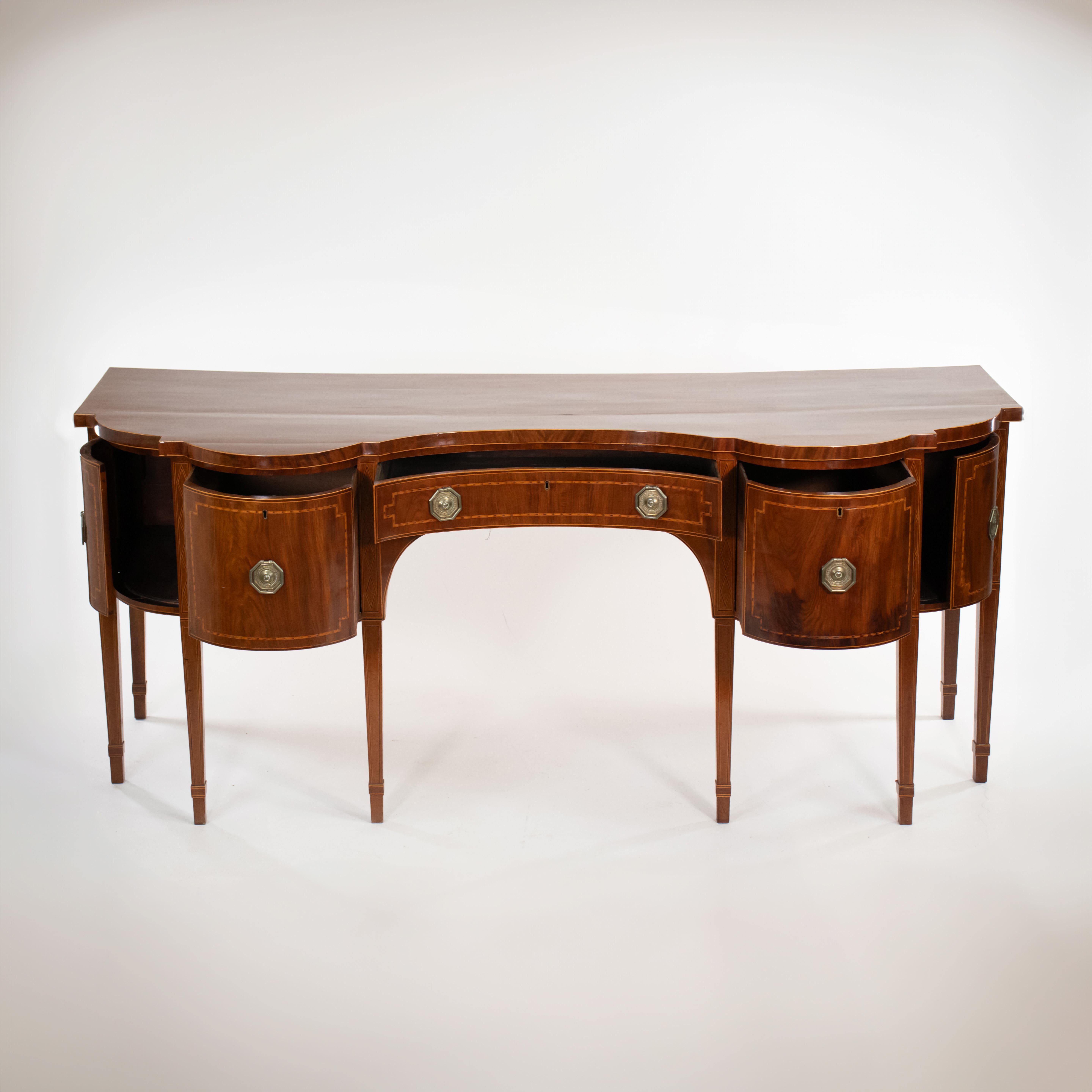 This elegant mahogany George III English sideboard features delicate satinwood inlay and stringing that complements its dynamic curves and shape. Crafted from mahogany and mahogany veneer, it boasts a natural deep and warm mocha coloring with