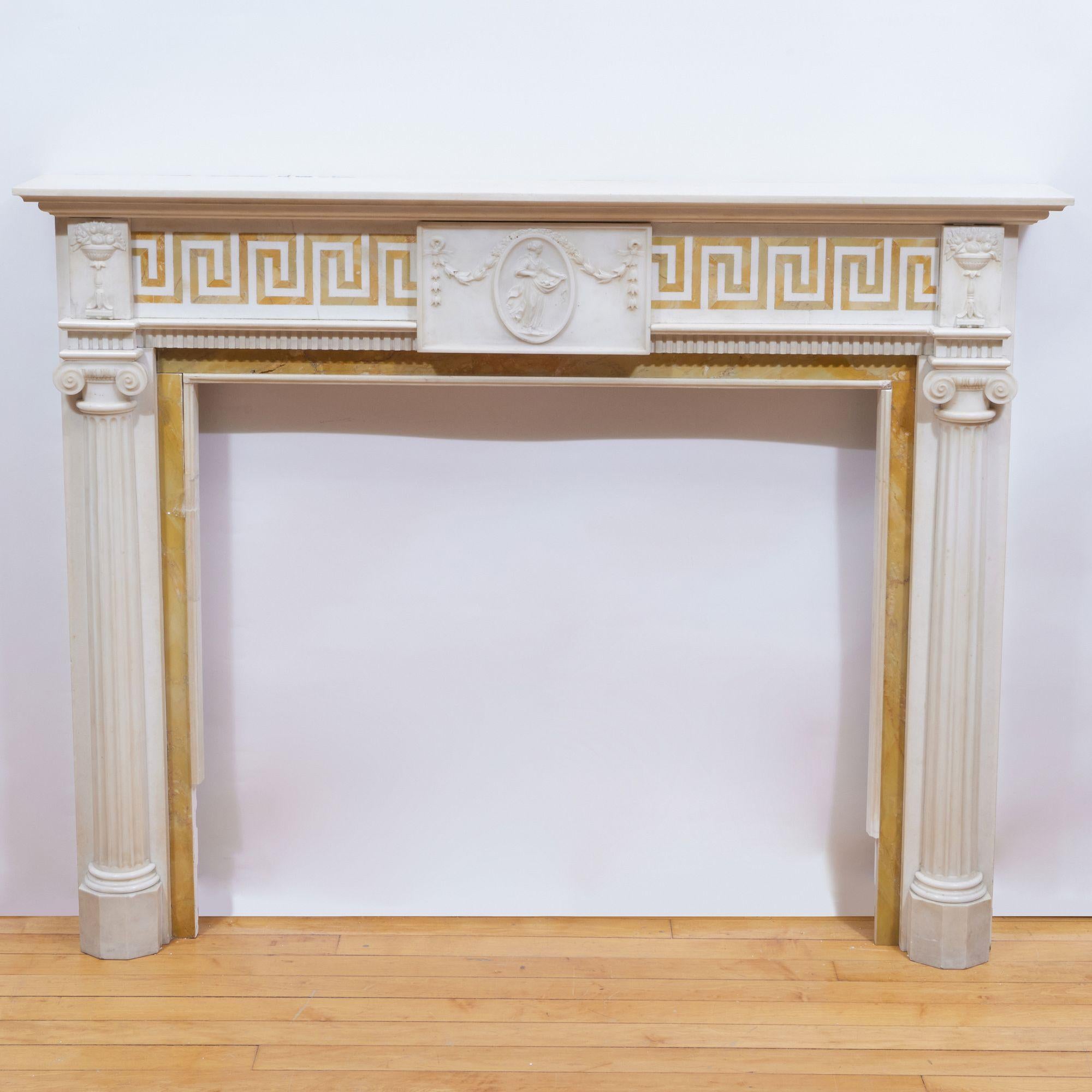 Mid-19th Century English Georgian Marble Fireplace Mantel.  Fluted Statuary Marble Ionic Half Columns supporting relief carved fruit epergne.  A carved central relief plaque of Flora with Neoclassical bellflower swags, flanked on each side by an