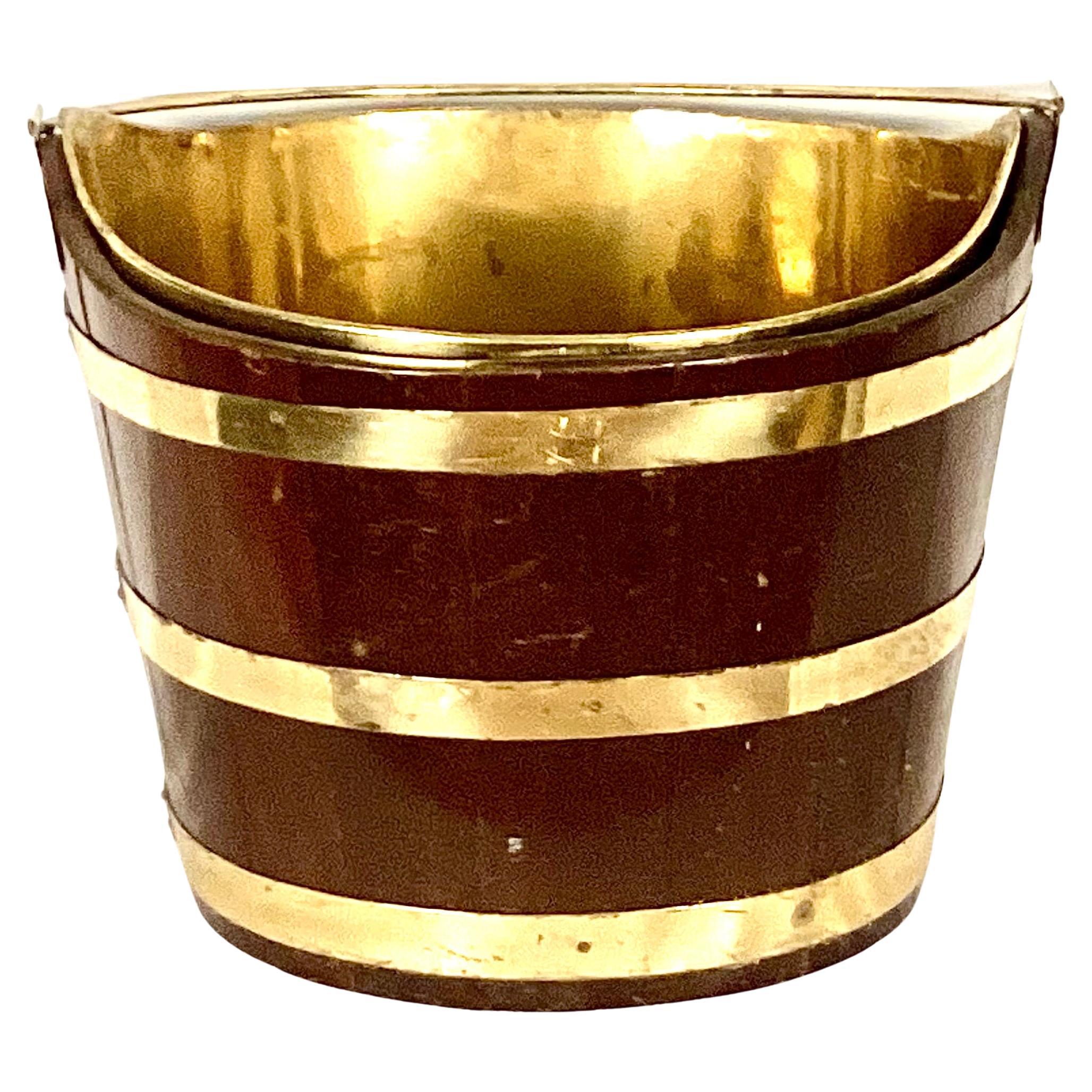 Large George III brass bound mahogany peat bucket. Bucket is on an oval shape and bound with three brass bands. The handle and removable liner are also brass. 