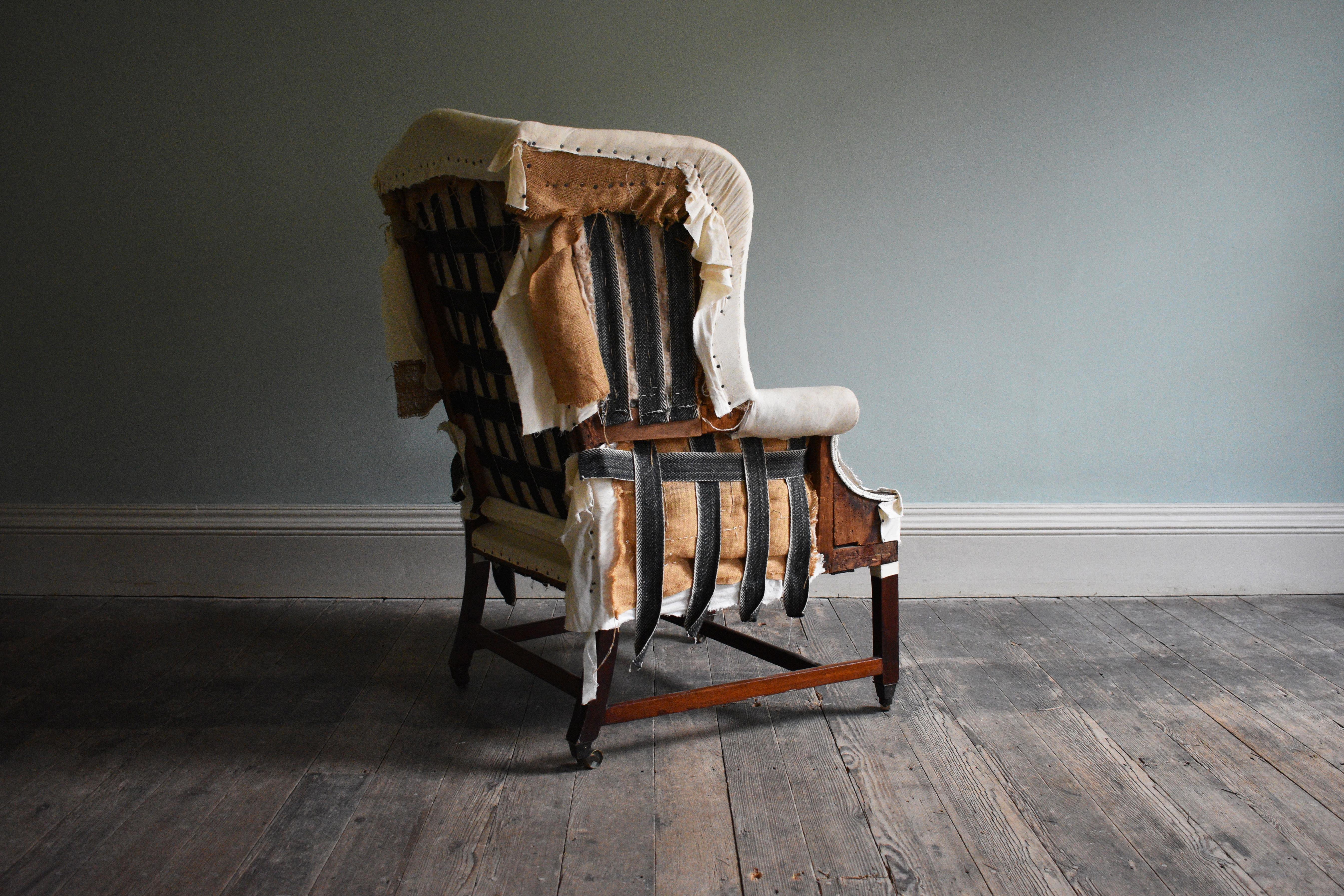George III Wingback Armchair

Fabric, wood and metal. An impressive George III wood-framed wingback style chair, with generous proportions, shaped back leading to long scrolled arms and standing on square taper mahogany legs with brass cup