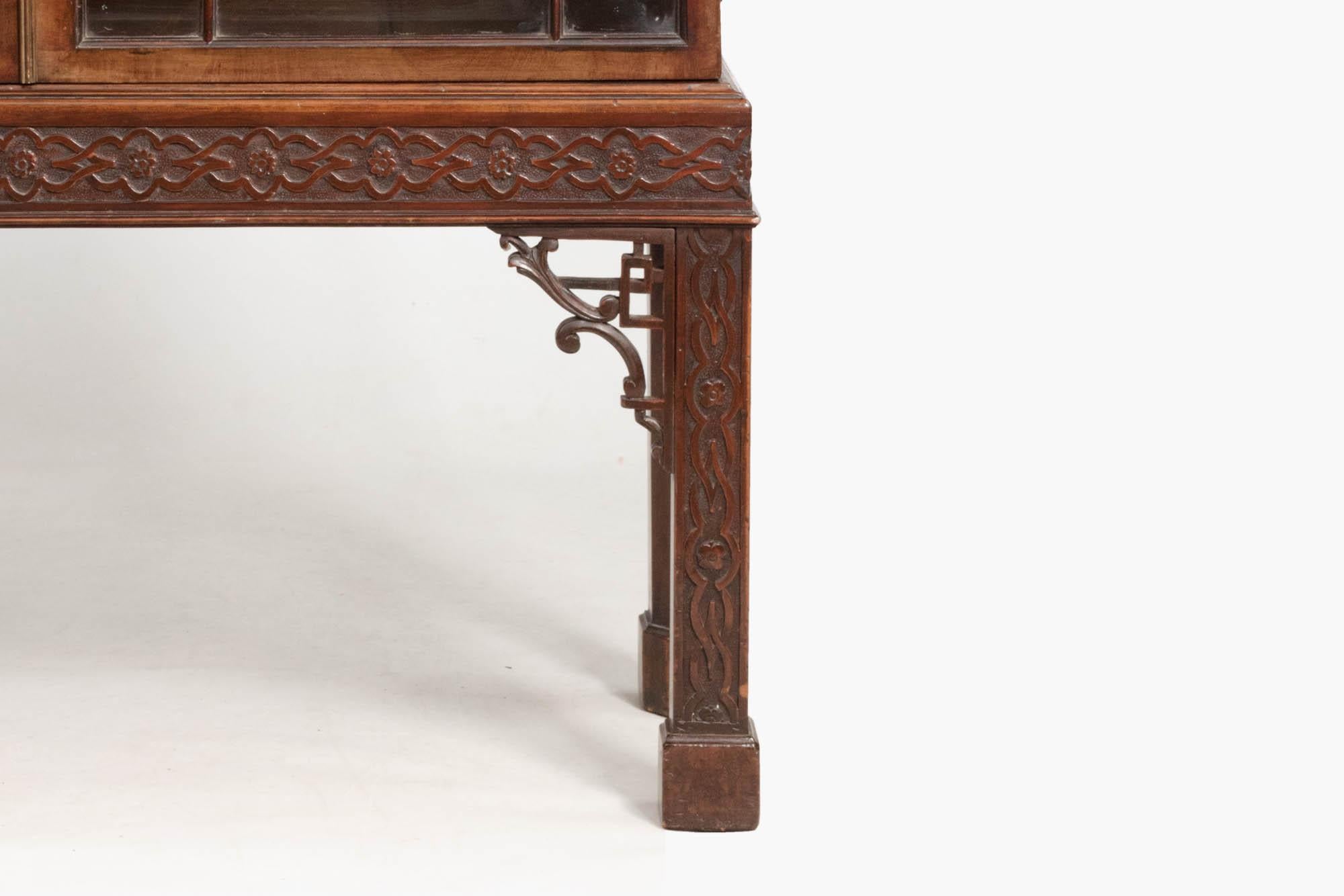 19th century Georgian mahogany Chinese Chippendale two-door display cabinet with finely carved details presenting seamless decoration across the rails and legs. The blind fretwork carved legs and pierced fine open fretwork spandrels compliment