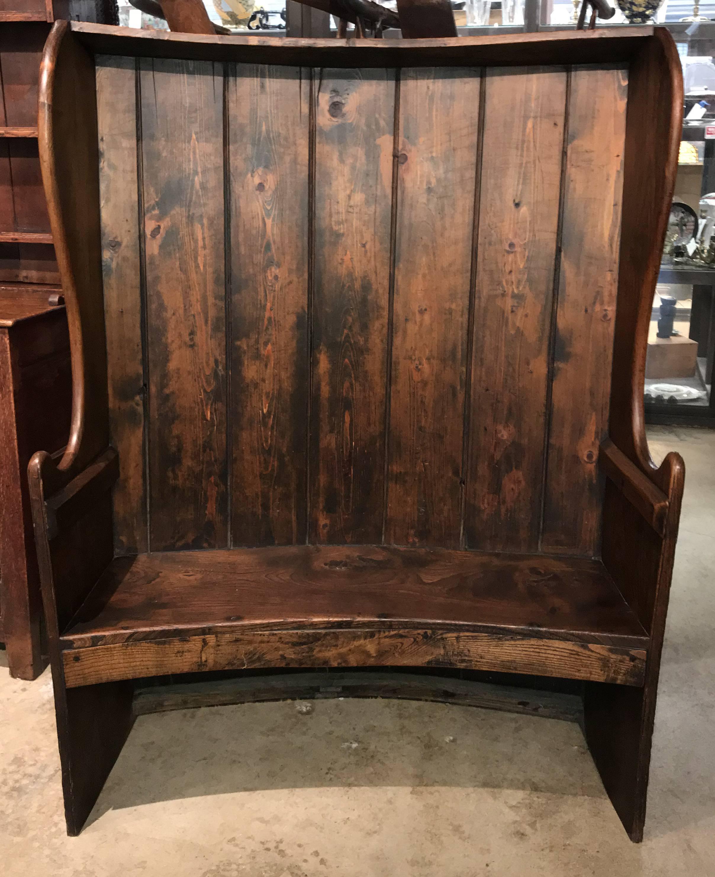 A wonderful form Georgian elmwood and pine curved settle with planked back, upswept arms, and conforming seat and apron. Includes a custom seat cushion. English, probably dating to the early 19th century. Very good overall condition, with
