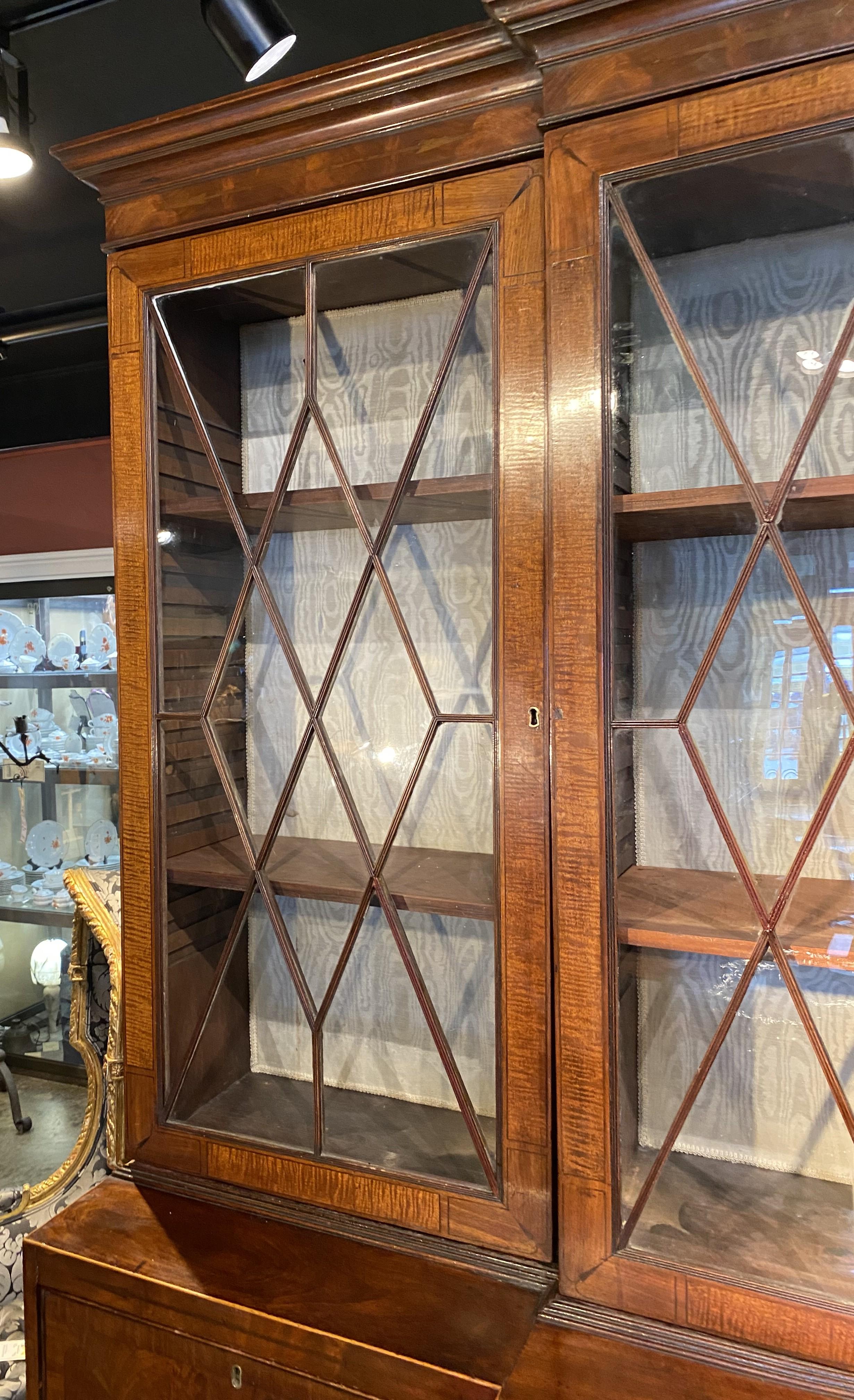 Une fabuleuse façade géorgienne de cinq pièces avec une corniche moulurée surmontant trois cas supérieurs séparés avec quatre portes en verre ajouré, ouvrant sur deux étagères réglables dans chaque section, avec un support textile satiné, sur une