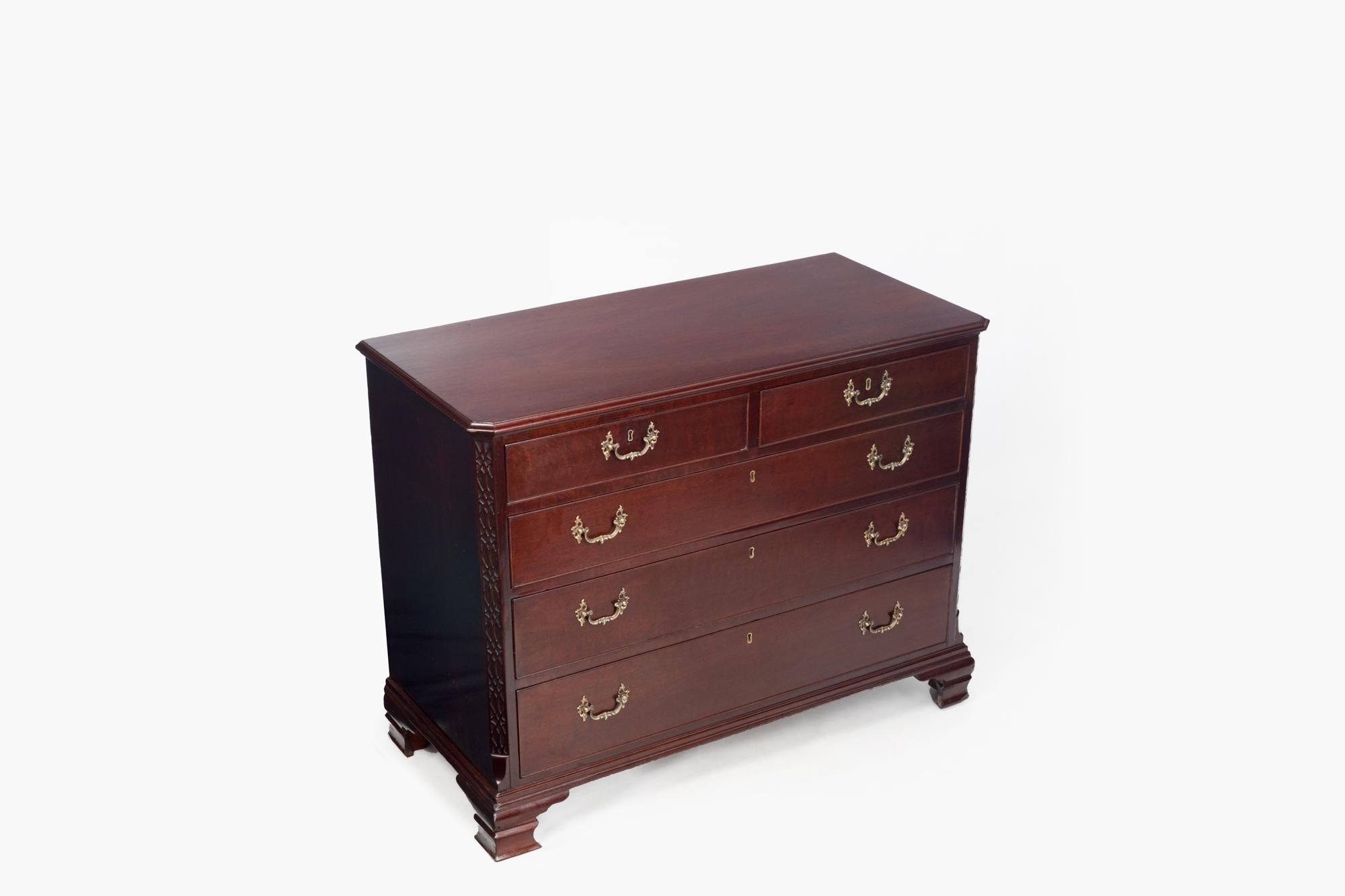 19th Century Georgian mahogany commode. Two small drawers sit above three large drawers each with pierced swan neck handles and brass escuteons. Blind fretwork pillars add detail to either side of the drawers with the piece raised on simple ogee