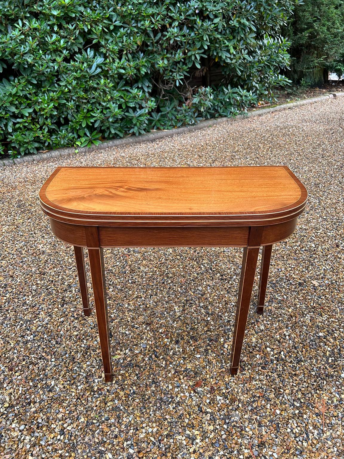 A high quality 19th Century Georgian Mahogany D-Shaped Card Table with Kingwood inlay and banding on square tapered legs. The two back legs swivels open, the top opens up to become a card table with a green baize inside.

Circa: