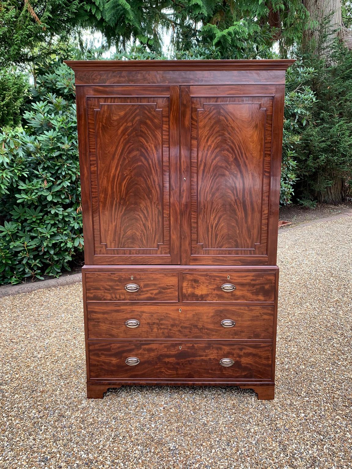 19th Century Georgian Mahogany Linen Press. The inside is fitted with a brass pole for hanging space . Below has two short and two long solid oak lined mahogany drawers with oval brass handles on bracket feet. Comes apart in three separate
