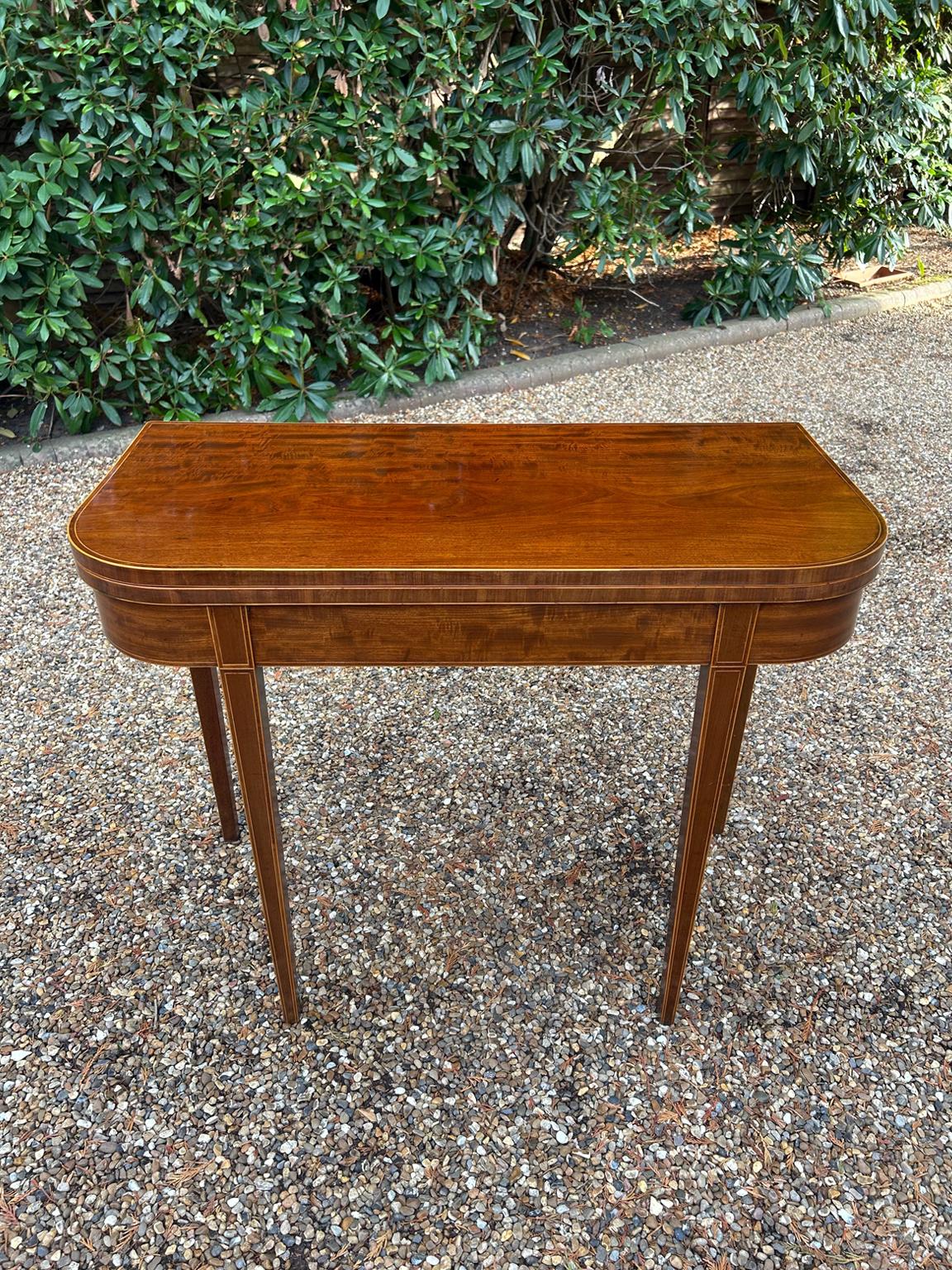 Table à thé en acajou de style géorgien du 19e siècle, avec incrustation de bandes transversales et de lignes sur l'ensemble de la table, sur des pieds carrés effilés. Les pieds arrière coulissent vers l'arrière pour se transformer en table à