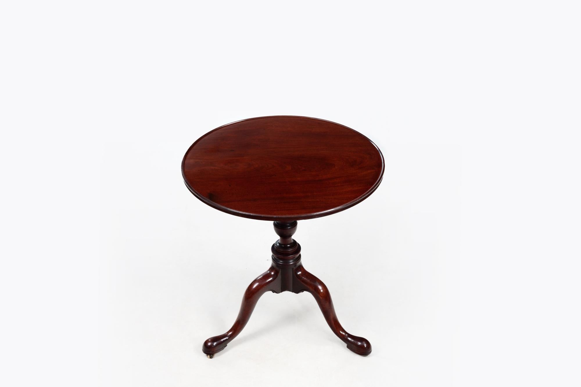 19th Century Georgian mahogany tip-up tea table. The round top supported by a turned baluster tripod base terminating on simple pad feet.