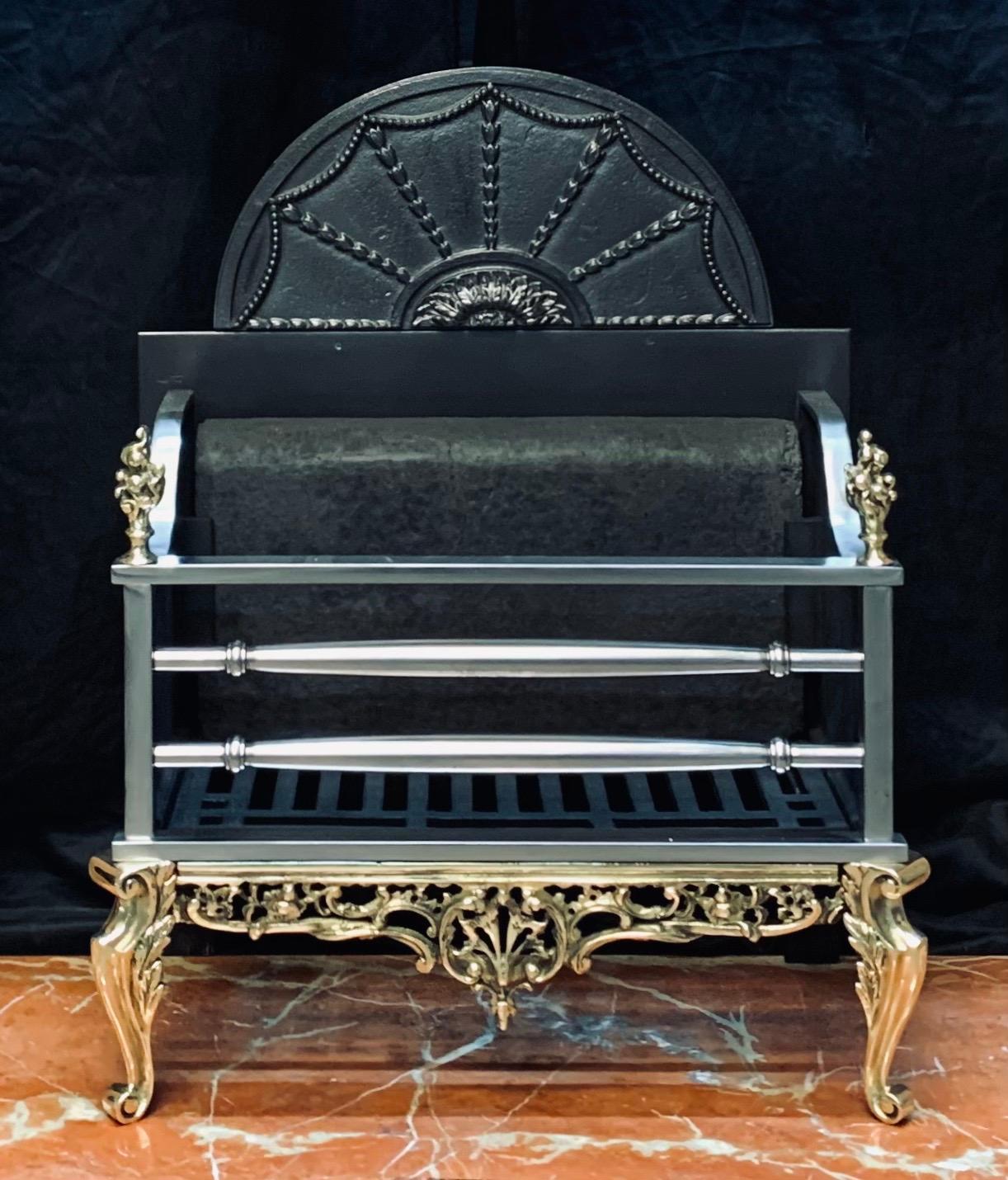 A charming 19th century Georgian style fire grate basket in polished brass and cast iron. A high cast decorated arched back plate, with its original fire stone, scalloped side cheeks surmounted with brass flame finials, below a pair of polished