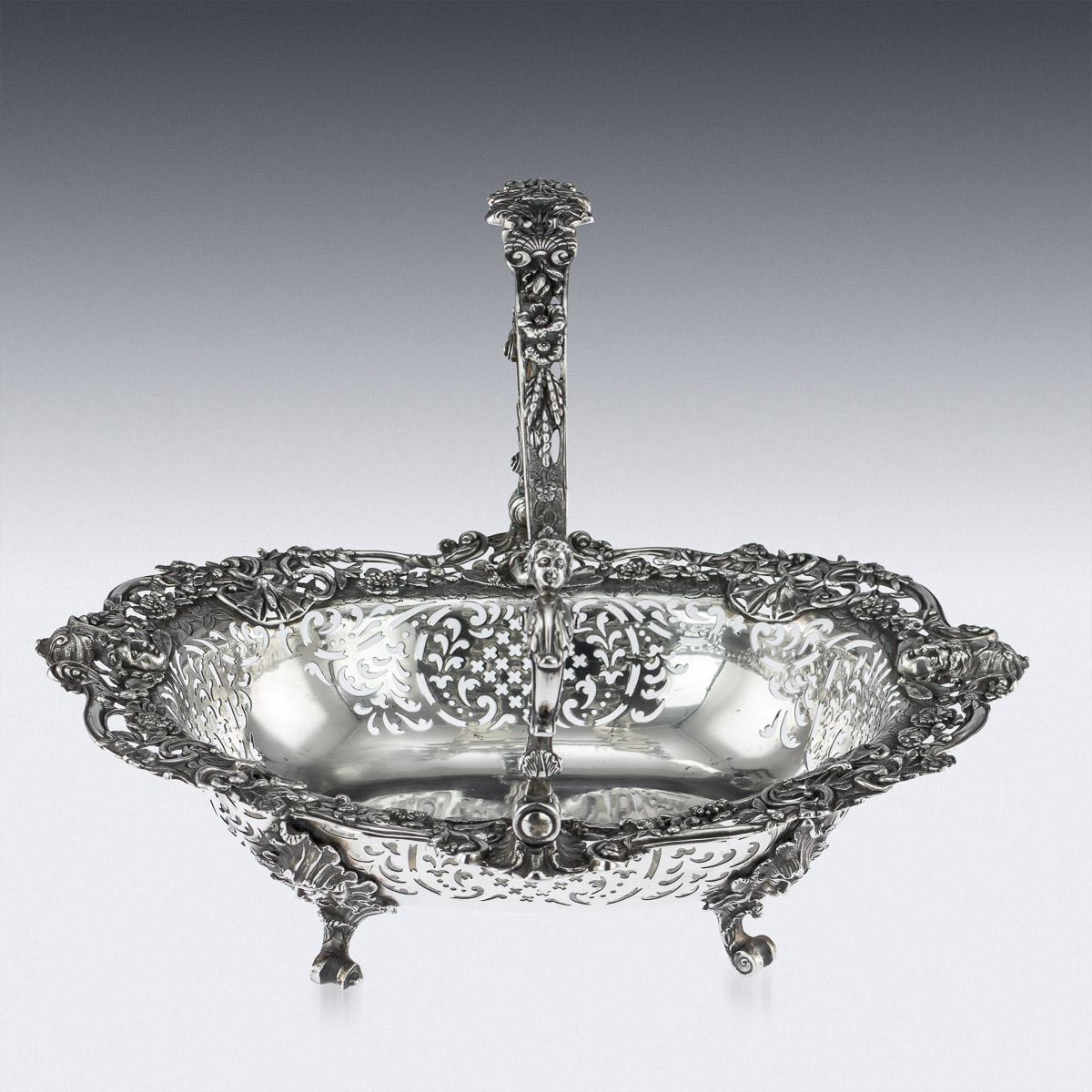 Antique 19th century Georgian solid silver basket, on four cast mask, ruffle and scroll feet, the shaped oval body pierced along the sides and applied with a border of cast and pierced winged masks, moths, festoons, flowers and foliage among