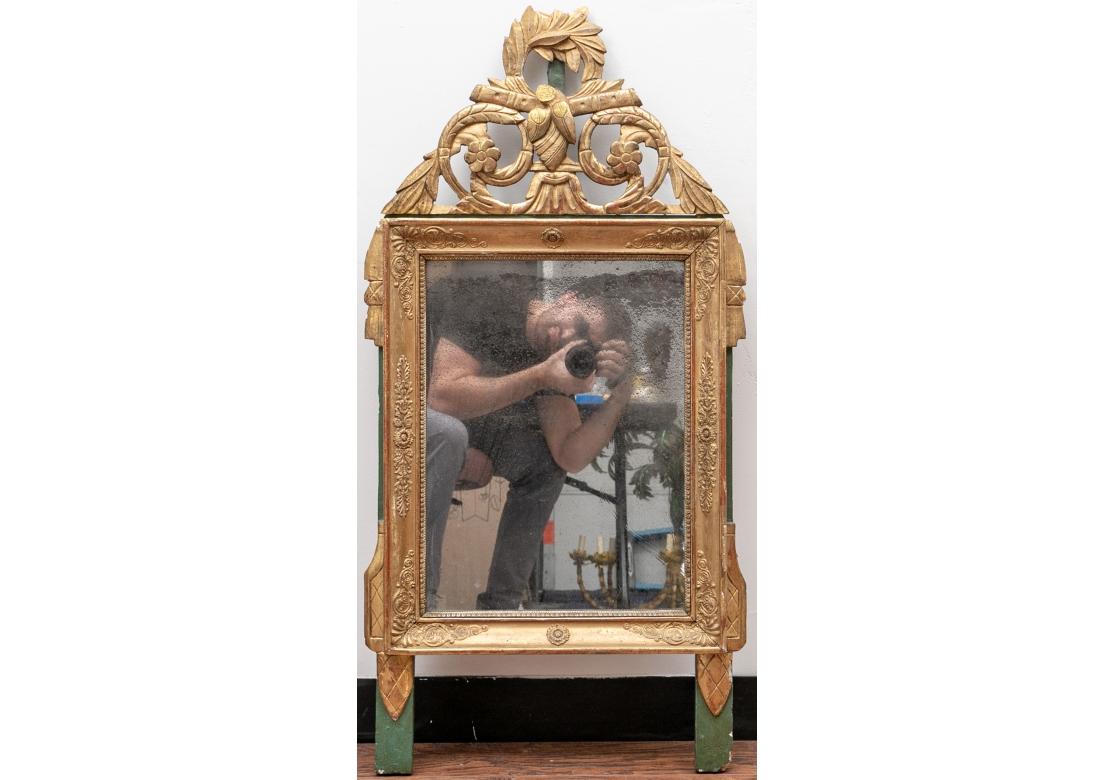Miroir doré du 19e siècle, de forme rectangulaire verticale, avec une gerbe de fleurs en relief sur le cadre biseauté, soutenu par un chevalet vert sauge avec des accessoires de suspension en fil de fer. Il est surmonté d'un décor sculpté et ajouré
