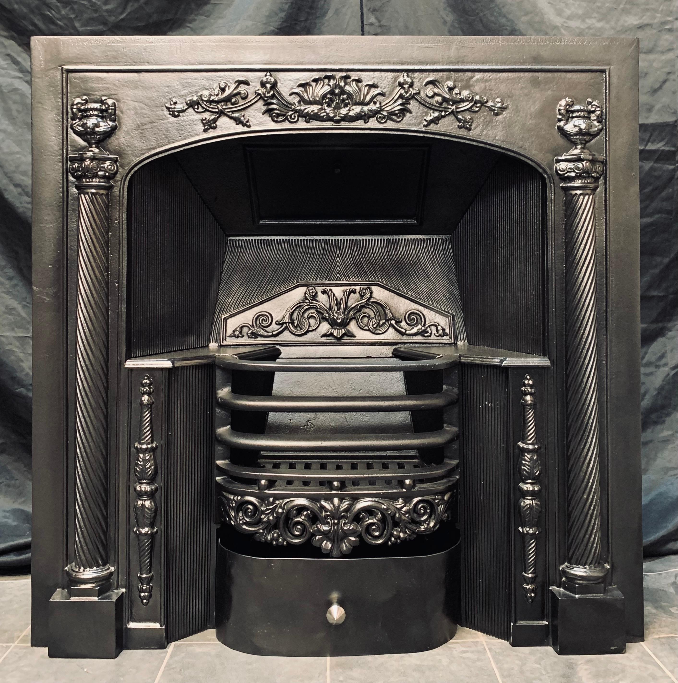 A smart and well balanced 19th century Georgian style hob grate fireplace insert. A large framed outer plate with a central raised embellishment flanked by two tall barley twist spindles capped by urns, and highlighted foot blocks. A central three